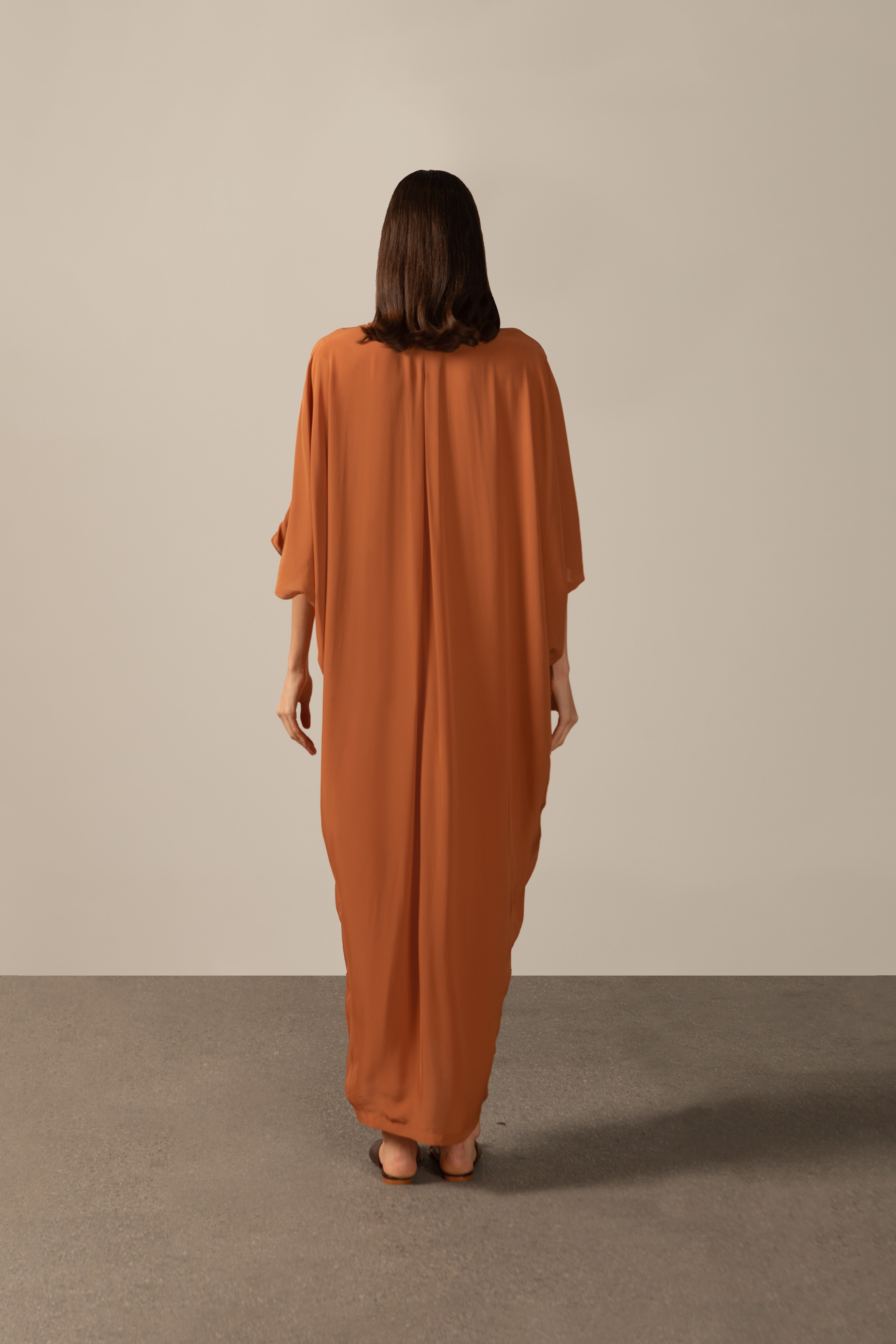 Model wearing the Geometric Long Kaftan cognac back from the HS25 with 100% viscose styled for a drinks by the pool look.   