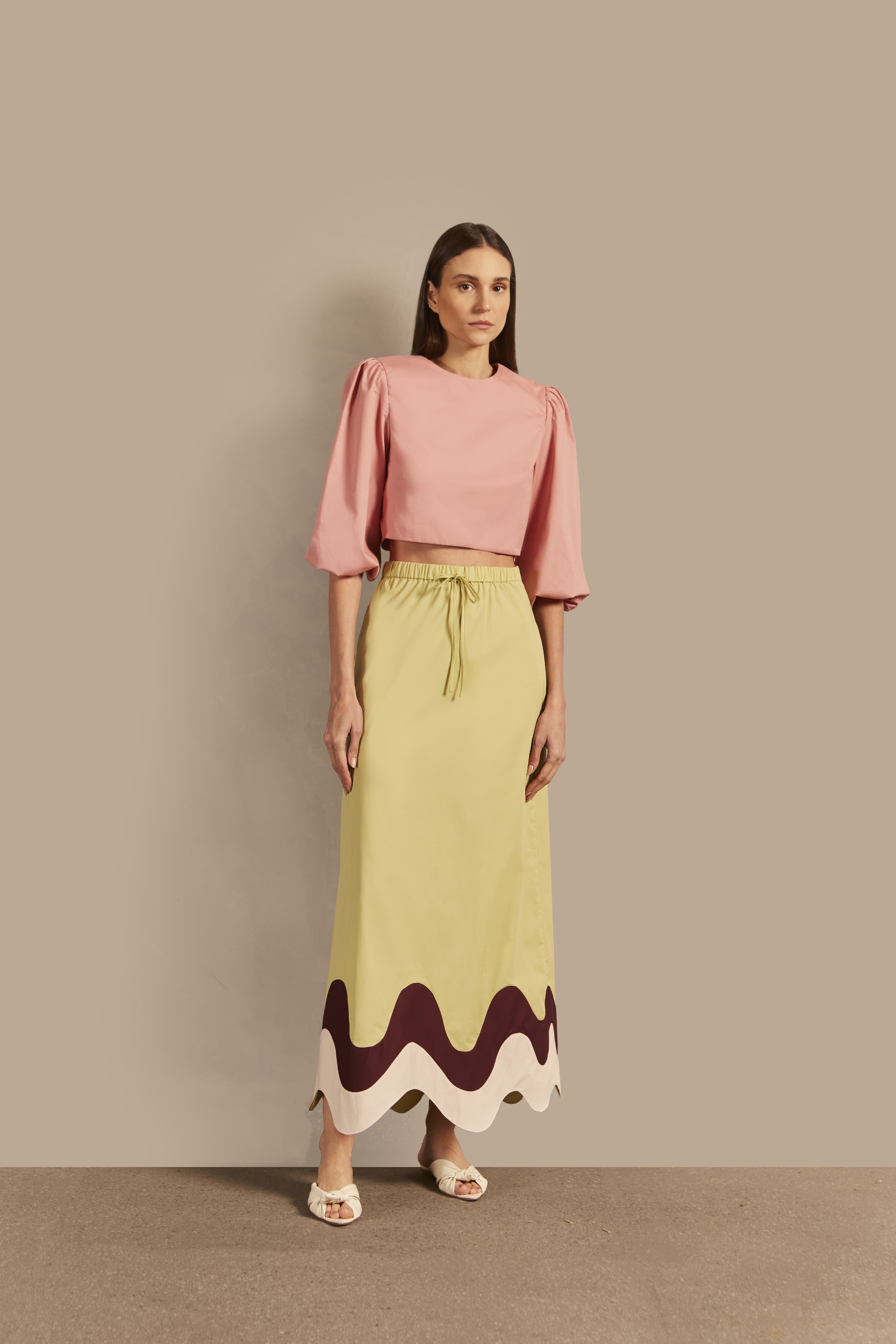 Model wearing the Giardino Solid Long Skirt Front showcasing its Sugarcane Green color on 98% Cotton 2% Elastane fabric, styled for an afternoon look.  