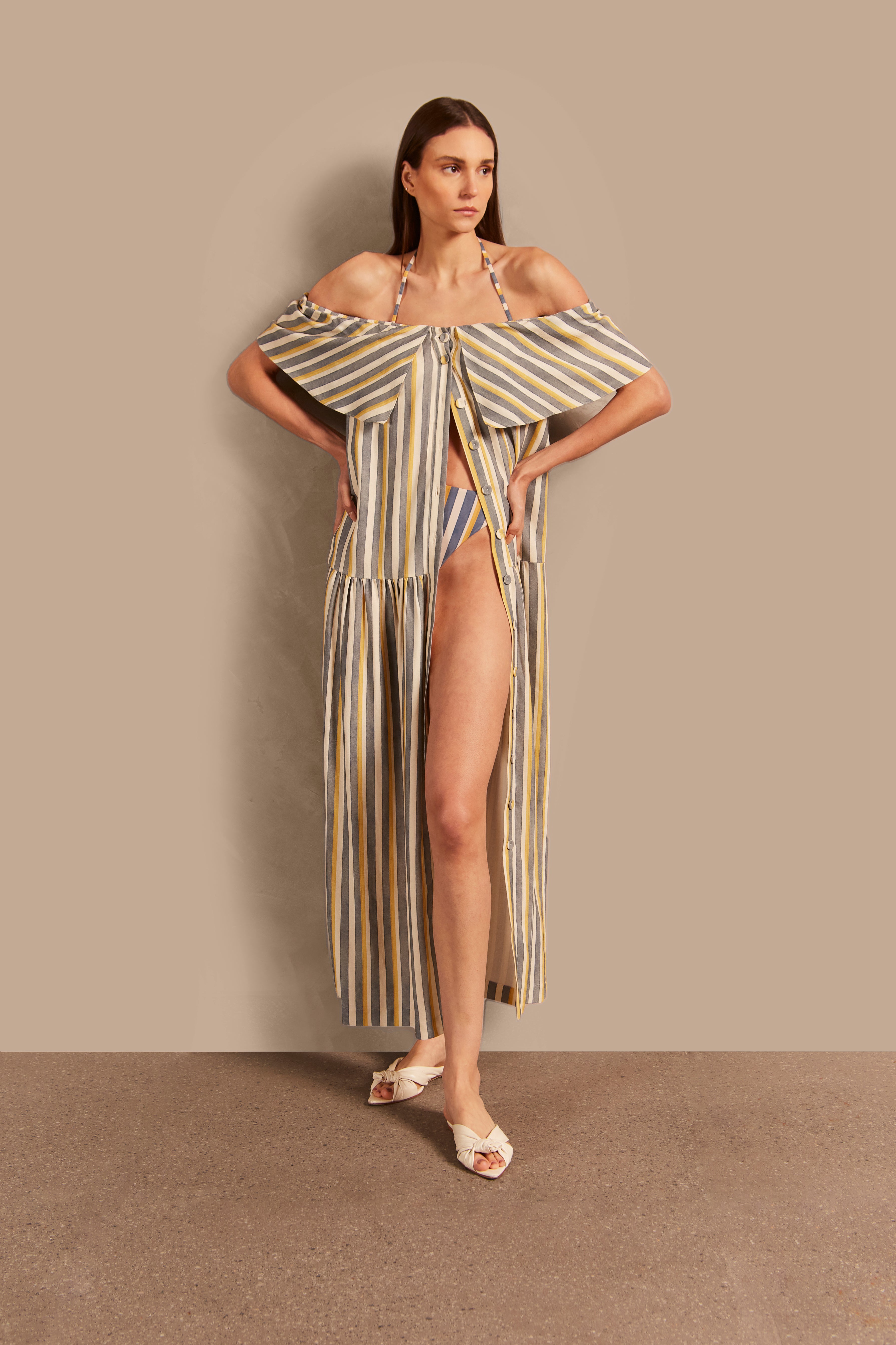 Model wearing the Golden Age Off-The-Shoulder Long Dress showcasing its vintage references with off white, blue and yellow print on a modal and linen fabric, styled for a casual look.