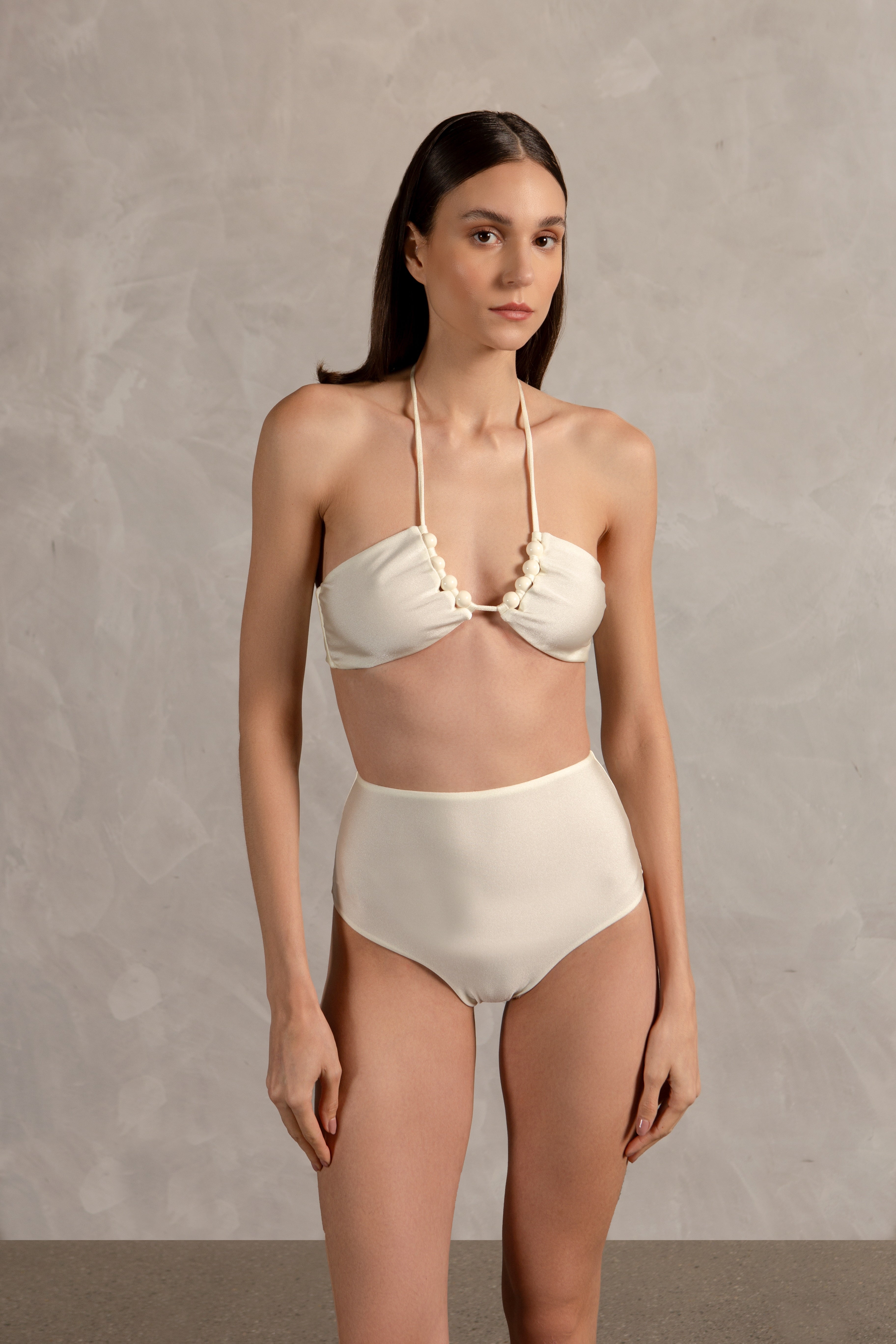 Model wearing the Golden Age Solid High-Waisted Bikini Close showcasing its ball-shaped applications with Off White print on 85% polyamide 15% spandex fabric, styled for a beachwear look.