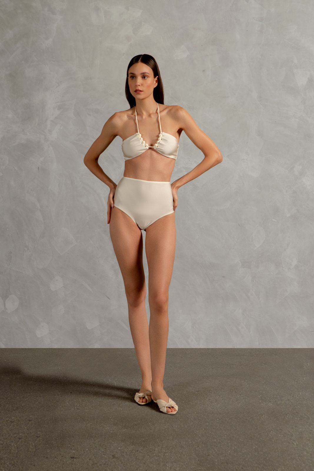 Model wearing the Golden Age Solid High-Waisted Bikini Front showcasing its ball-shaped applications with Off White print on 85% polyamide 15% spandex fabric, styled for a beachwear look.