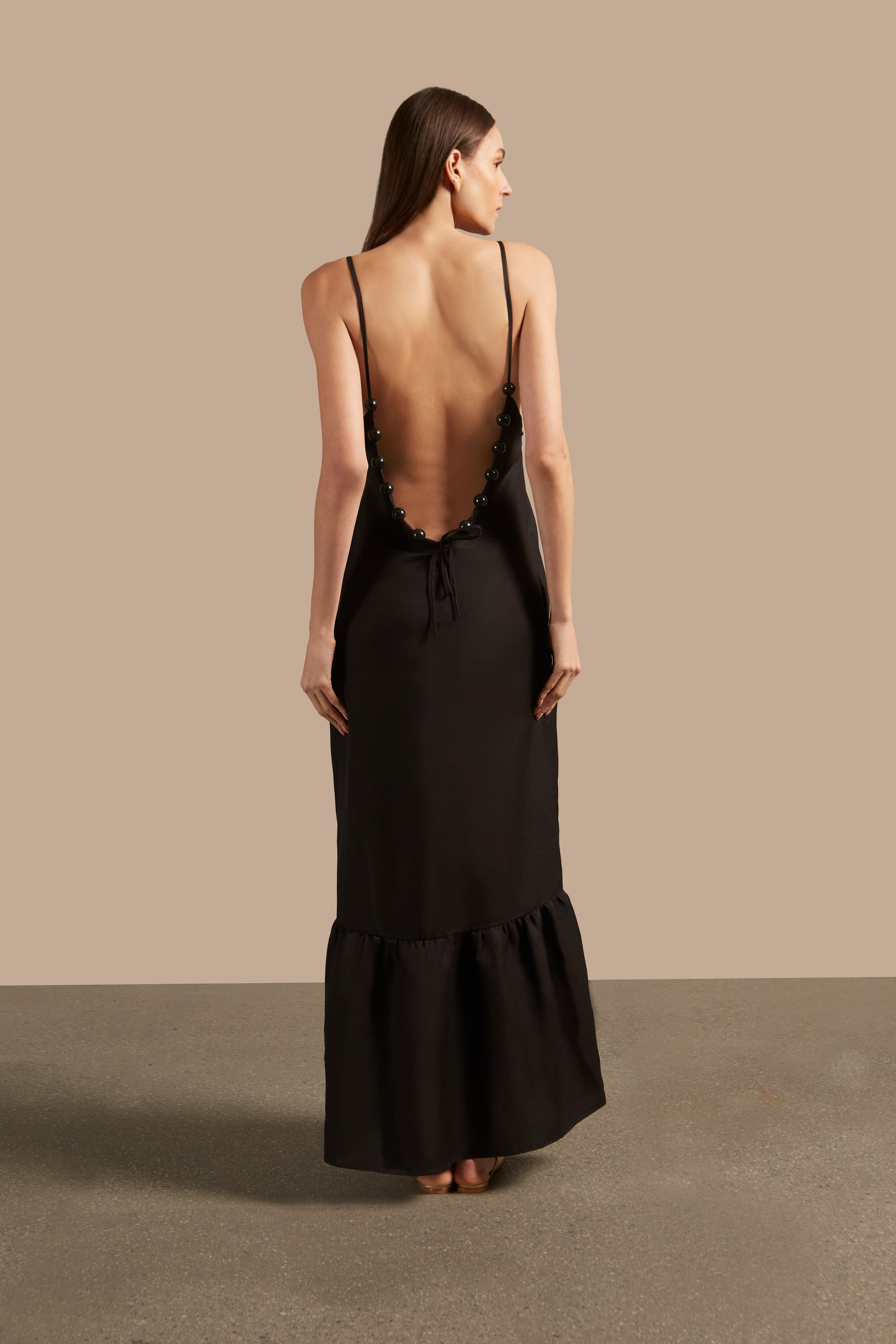 Back view of the Golden Age Solid Straps Long Dress in black, showcasing its elegant V-back neckline with decorative trims.