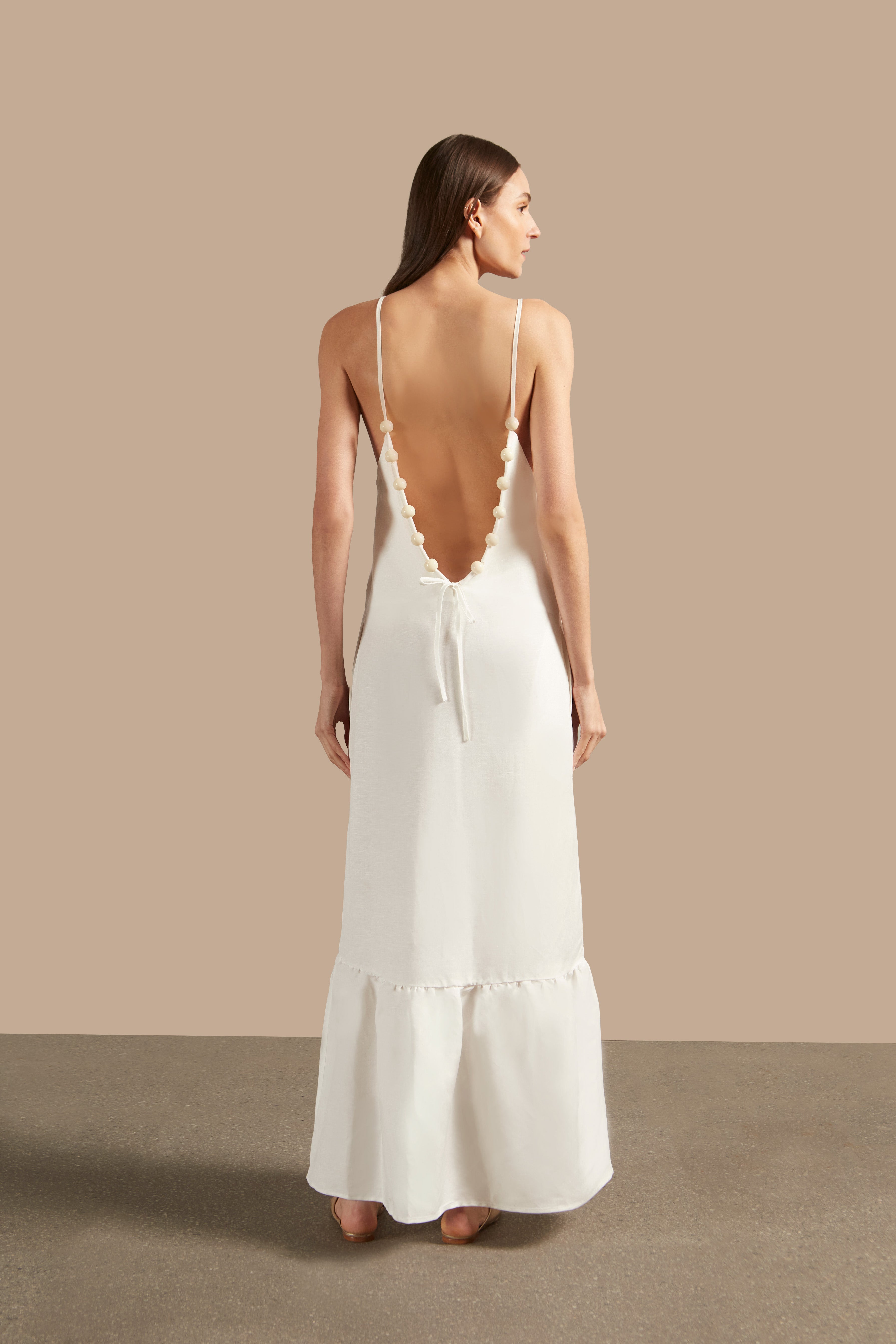 Back view of the Golden Age Solid Straps Long Dress in off-white, featuring a V-back neckline with ball-shaped trims