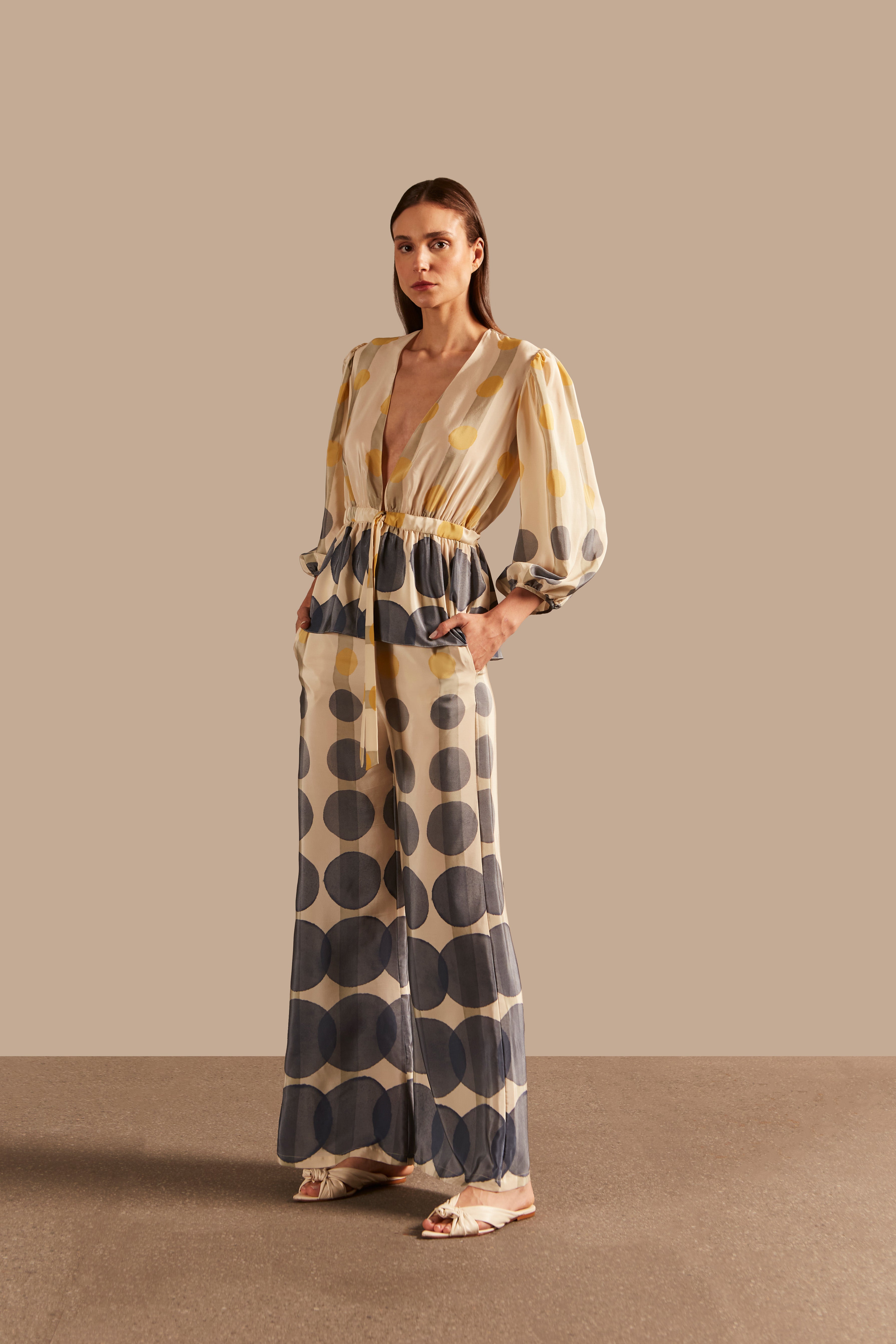 Model wearing the Golden Age Voluminous Sleeves Shirt showcasing the front of it's vintage references with Blue, Off White and Yellow print and a Deep V-Neckline on a silk fabric.