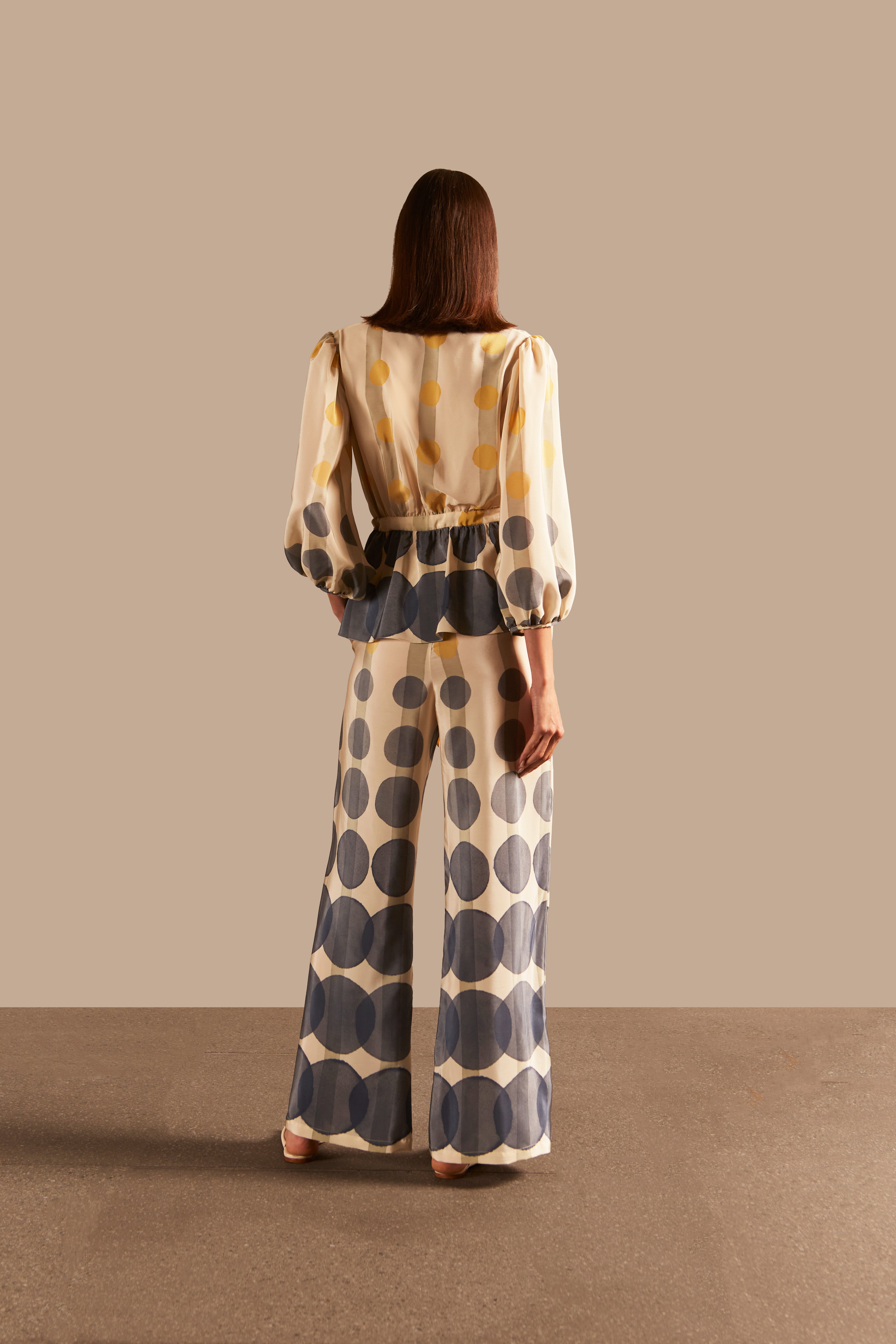 Full back view of the Golden Age Wide-Leg Pants, highlighting the bold geometric print in off-white, blue, and yellow on silk fabric.