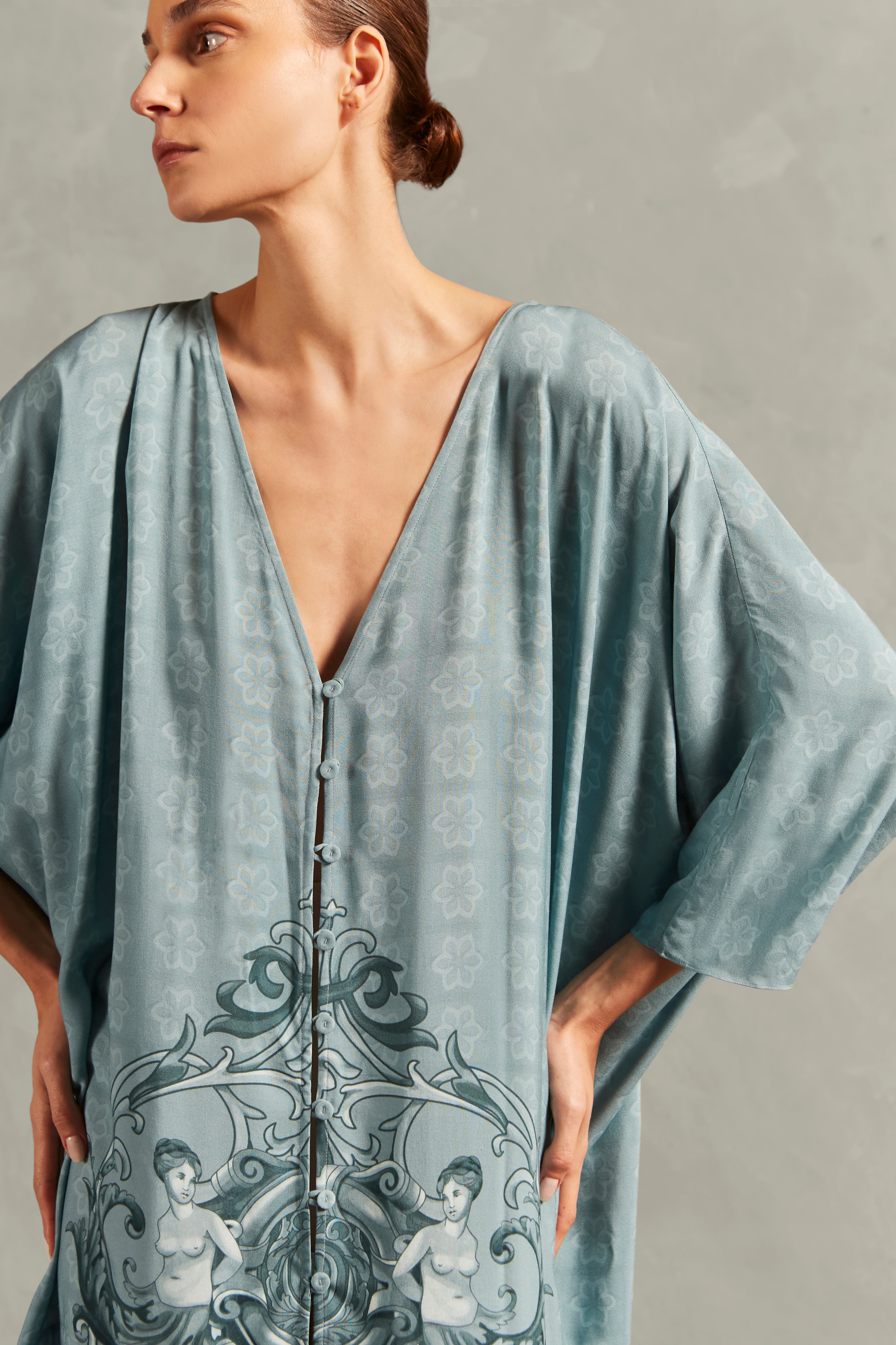 Model wearing the Hera Buttoned Long Robe Detail showcasing its vintage references with Blue print on 100% Viscose fabric, styled for a resort look. 