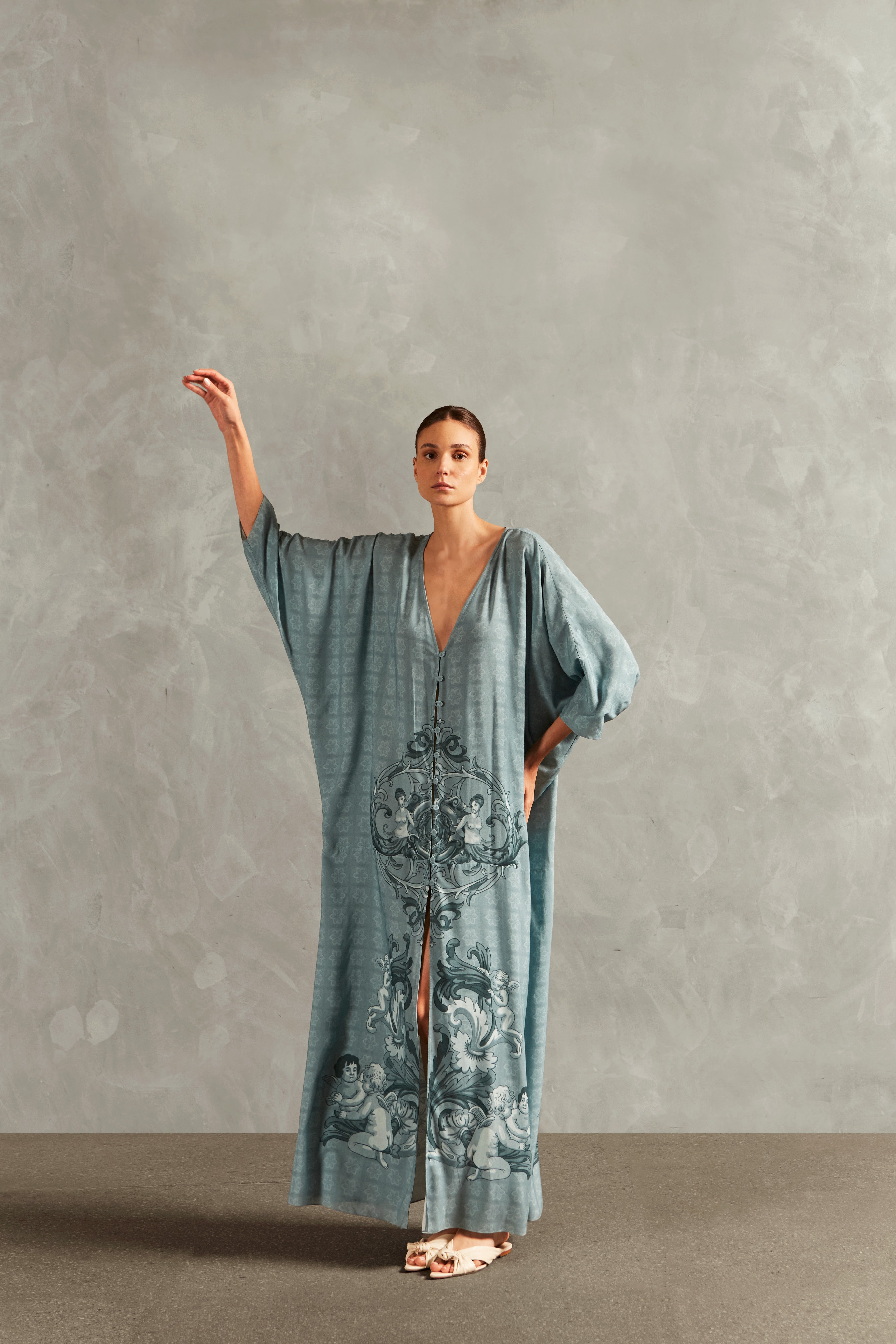 Model wearing the Hera Buttoned Long Robe Front showcasing its vintage references with Blue print on 100% Viscose fabric, styled for a resort look. 