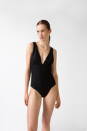 Model wearing the Solid V-Neck Swimsuit front, made from 85% polyamide 15% elastane, styled for a beachwear look 