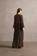 Model wearing the Mobile Wide-Leg Pants Back showcasing its contemporary elements with coffee print on 100% silk fabric used with bikini, styled for a resort look.