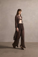 Model wearing the Mobile Wide-Leg Pants Front showcasing its contemporary elements with coffee print on 100% silk fabric used with bikini, styled for a resort look.