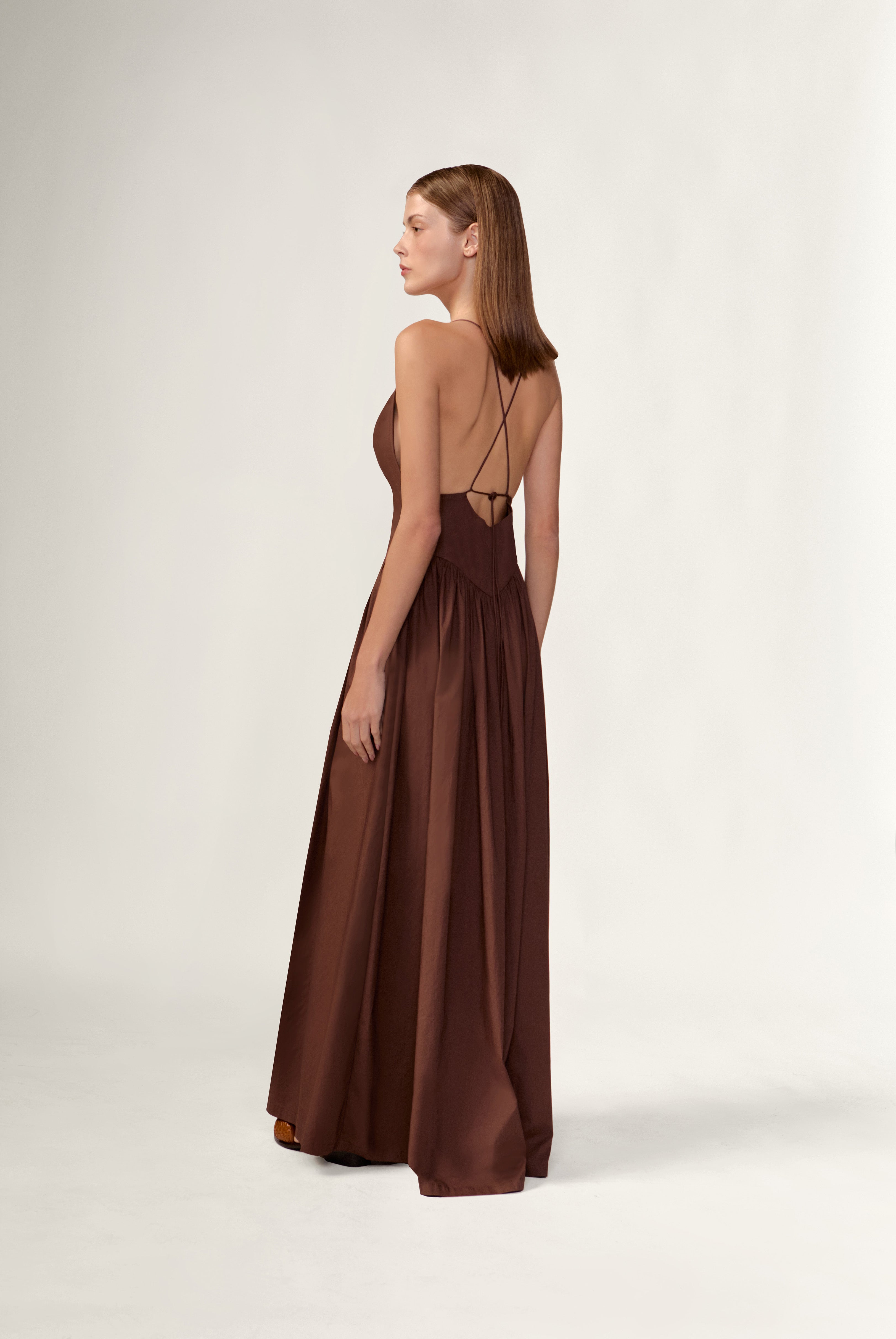 Model wearing the Opulence Deep V-Neck Maxi Dress back color brown made with 97% Cotton 3% Elastane,  styled for a dinner look 