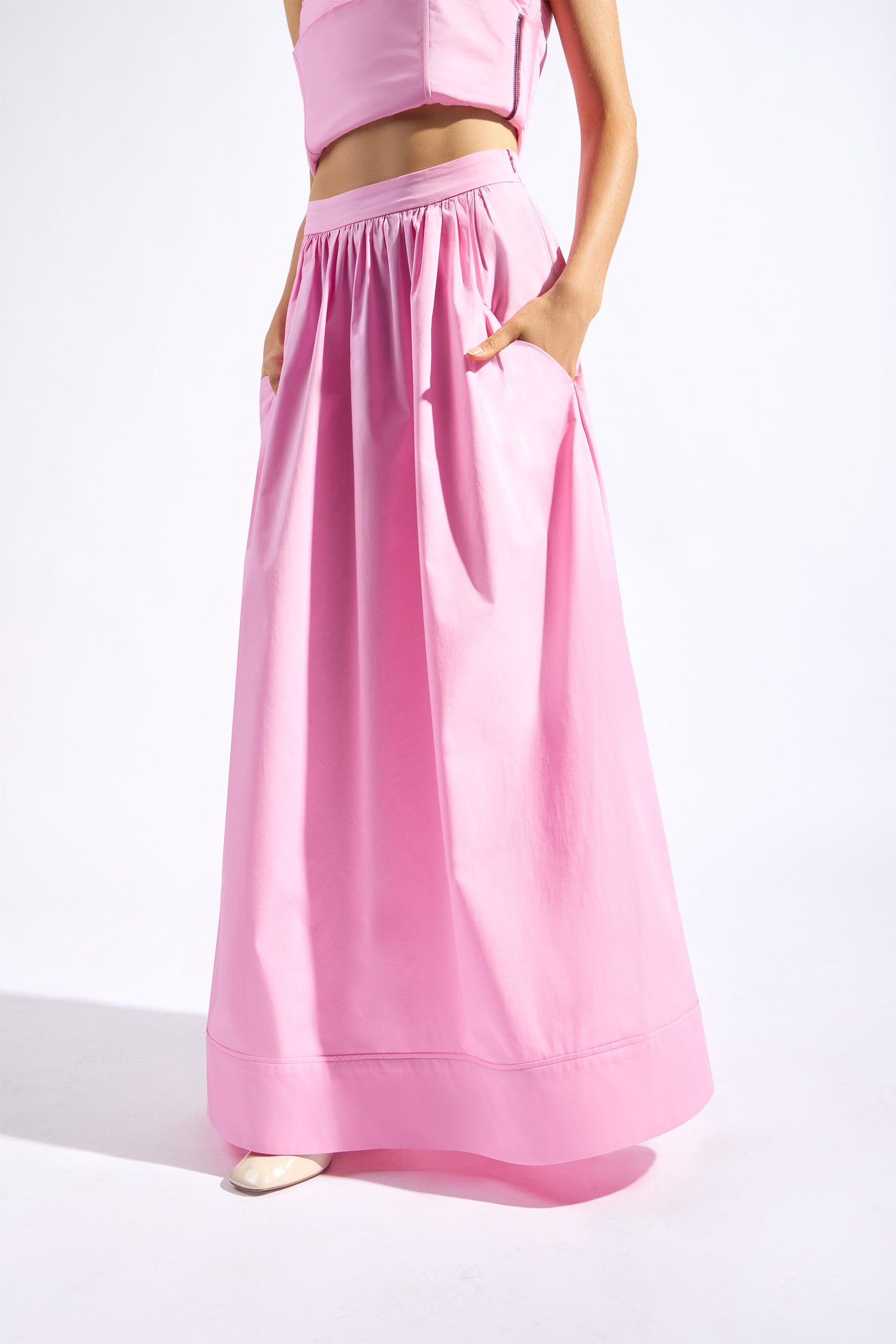 Model wearing the Opulence Maxi Skirt back color light pink made with 97% Cotton 3% Elastane,  styled for resortwear look 