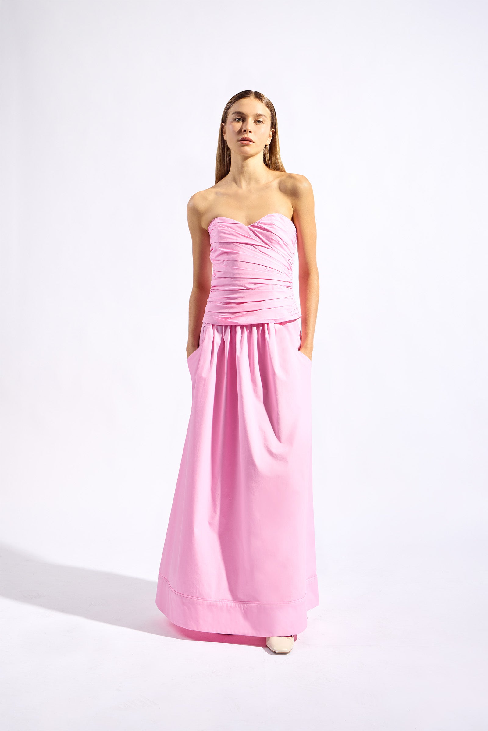 Model wearing the Opulence Maxi Skirt front color light pink made with 97% Cotton 3% Elastane,  styled for resortwear look 