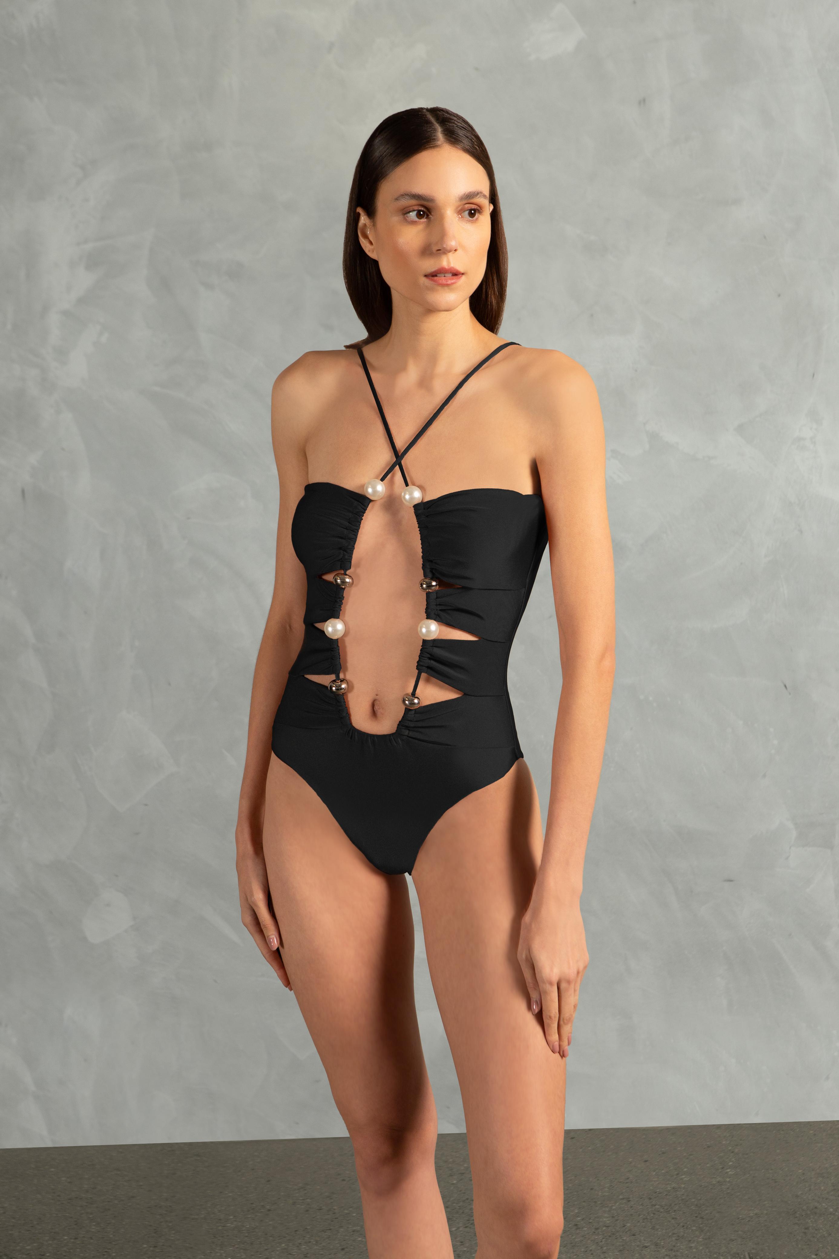 Model wearing the Oysters Solid Cut-Out Swimsuit With Pearls Front showcasing its Black print with Cut-outs and Pearls Applications on 85% polyamide 15% spandex fabric, styled for a beachwear look.