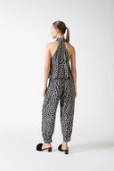Model wearing the Pois One-Shoulder High-Neck Jumpsuit navy back from the HS25 with 100% viscose styled for a drinks at sunset look.    