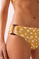 Model wearing the Polka Dots Bandeau Bikini detail color cashew yellow, made from 85% polyamide 15% elastane, styled for a beachwear look