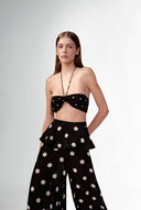 Model wearing the Polka Dots Bandeau Top detail color black, made with 100% viscose fabric, styled for resortwear look 