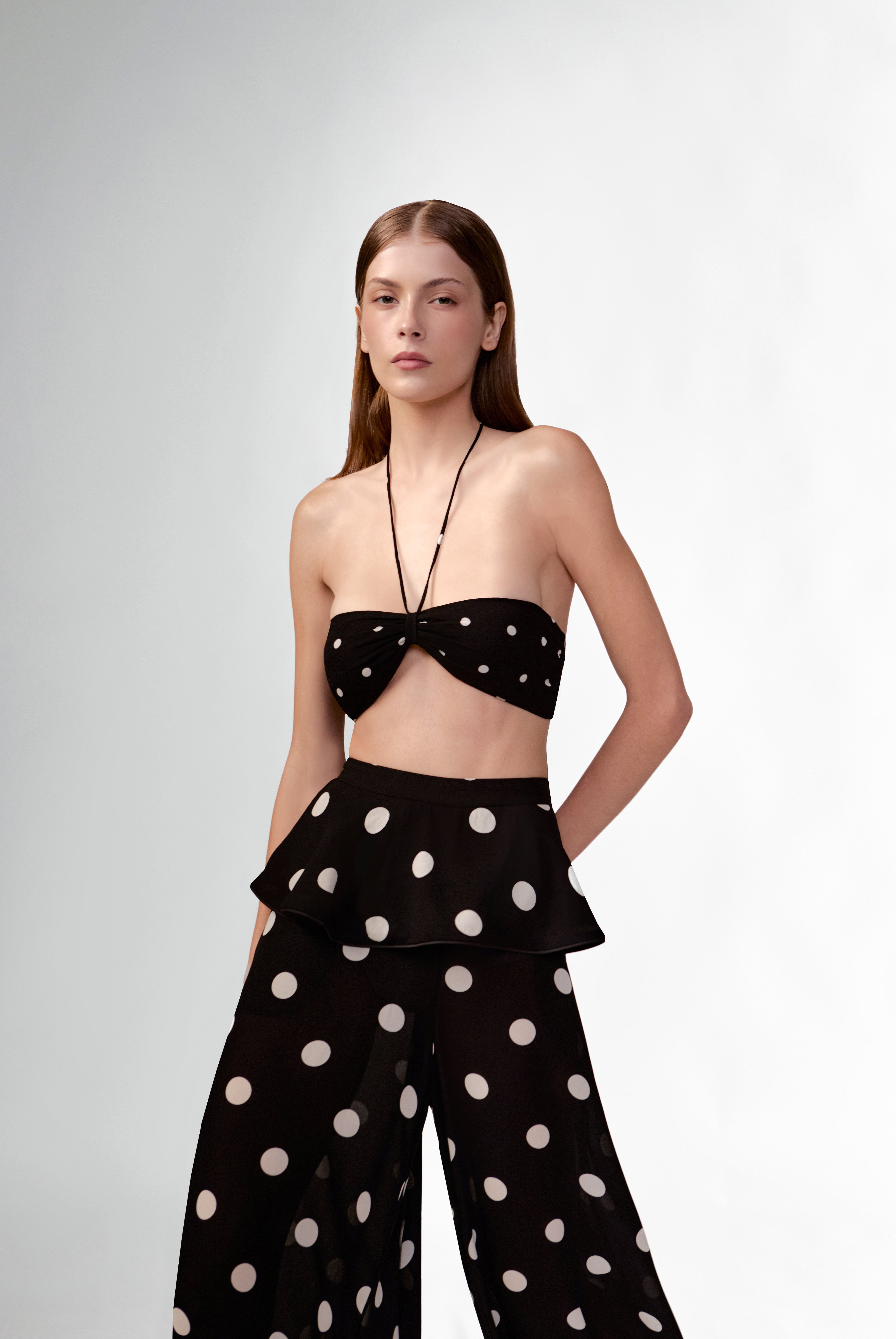 Model wearing the Polka Dots Bandeau Top detail color black, made with 100% viscose fabric, styled for resortwear look 