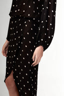 Model wearing the Polka Dots Long Sleeve Maxi Dress detail hem showcasing its black color on 100% Viscose fabric, styled for an evening look.  