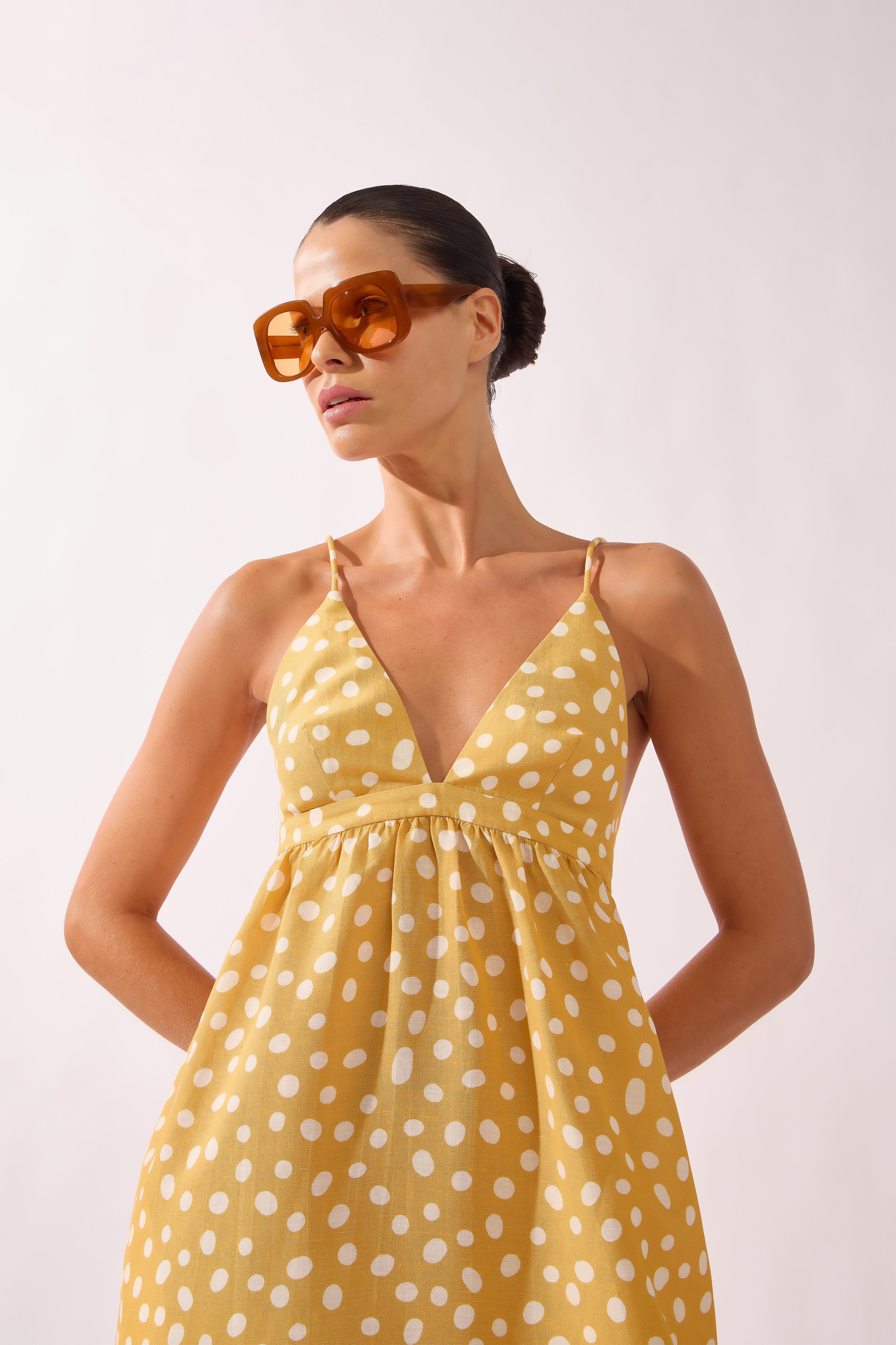 Model wearing the Polka Dots Maxi Dress detail color cashew yellow, made from 55% linen 45% viscose, styled for a resort look