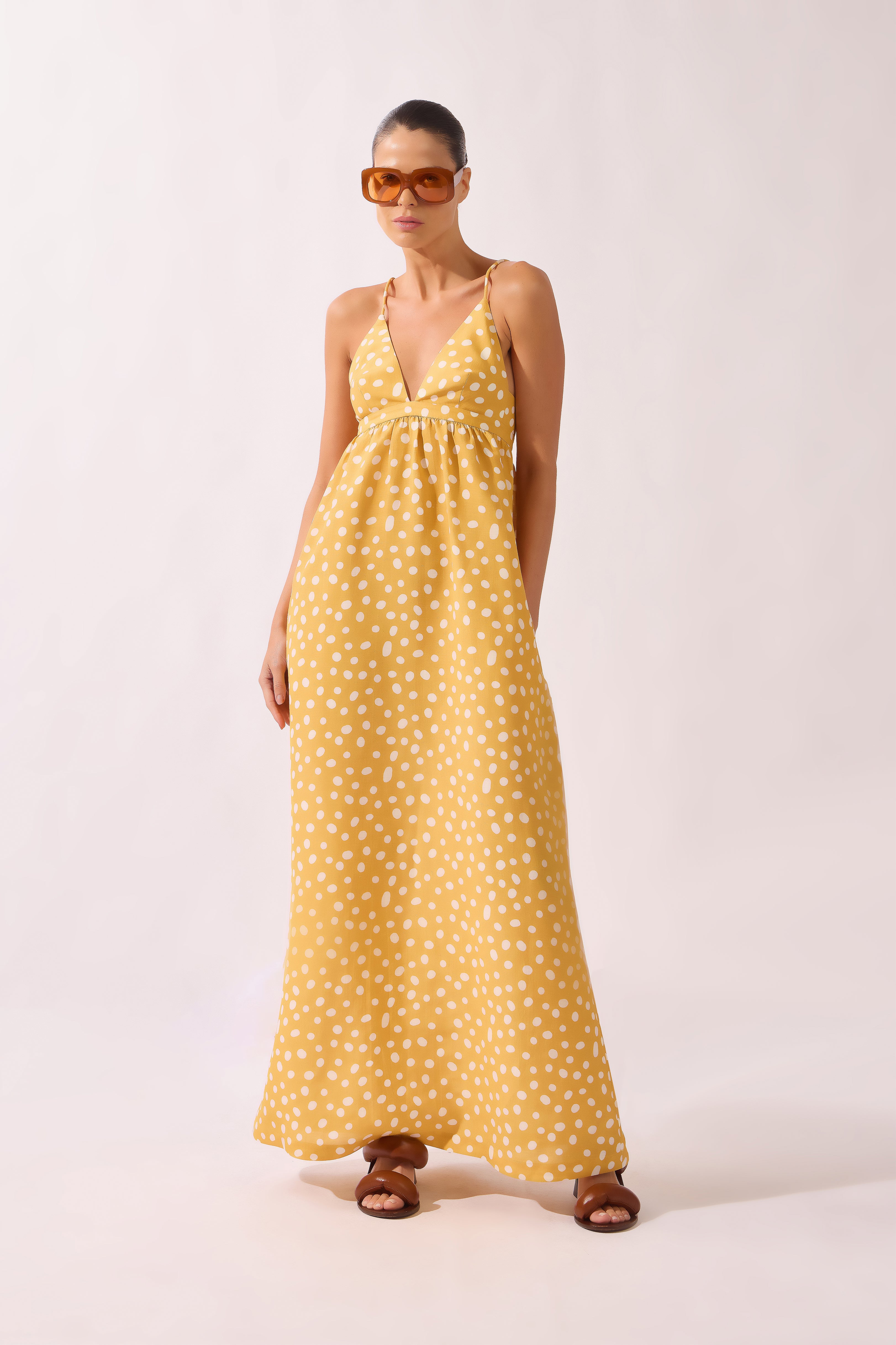 Model wearing the Polka Dots Maxi Dress front color cashew yellow, made from 55% linen 45% viscose, styled for a resort look