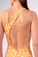 Model wearing the Polka Dots One-Shoulder Swimsuit detail color cashew yellow, made from 85% polyamide 15% elastane, styled for a beachwear look