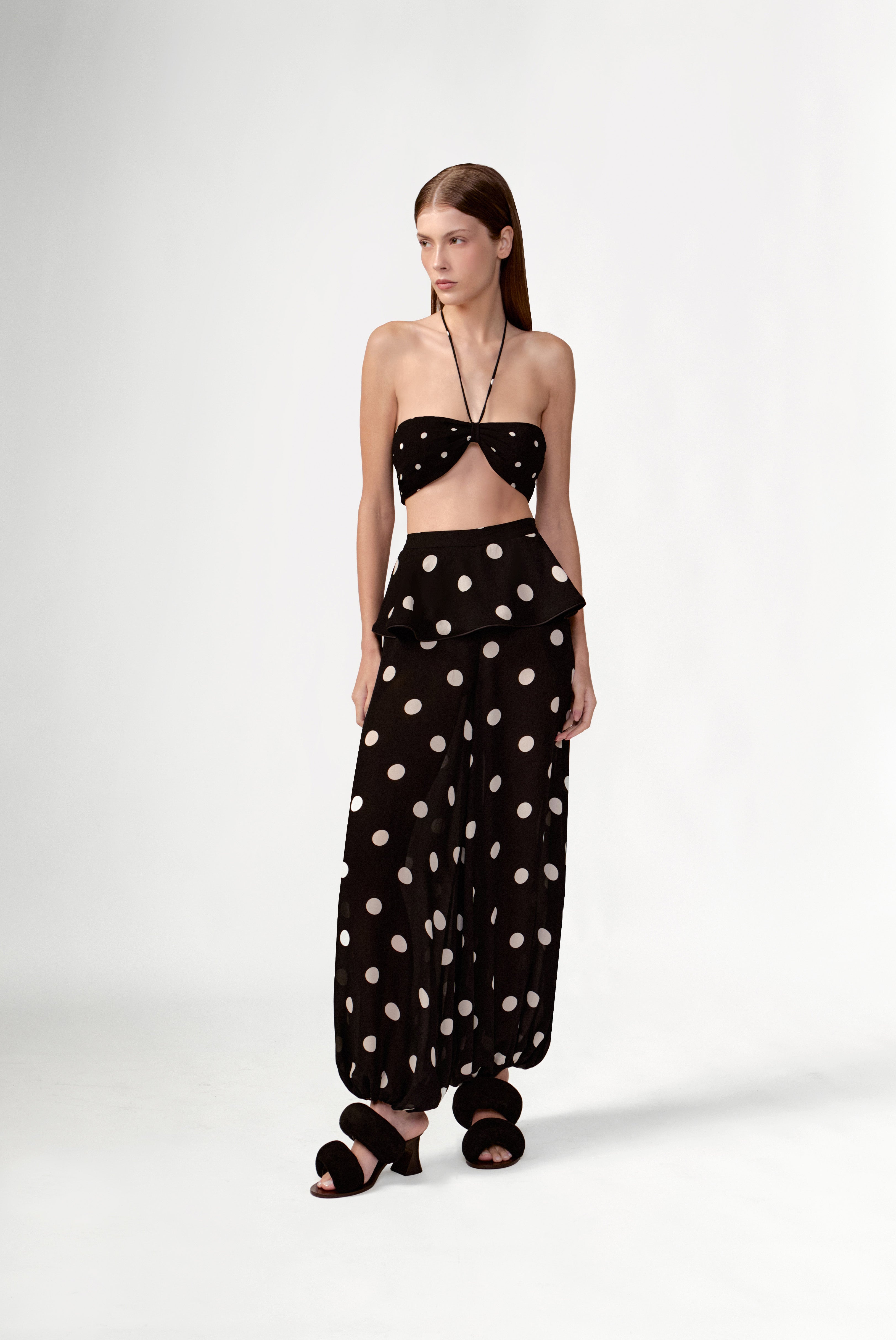 Model wearing the Polka Dots Peplum Maxi Pants detail color black made with 100% viscose, styled for resortwear look 