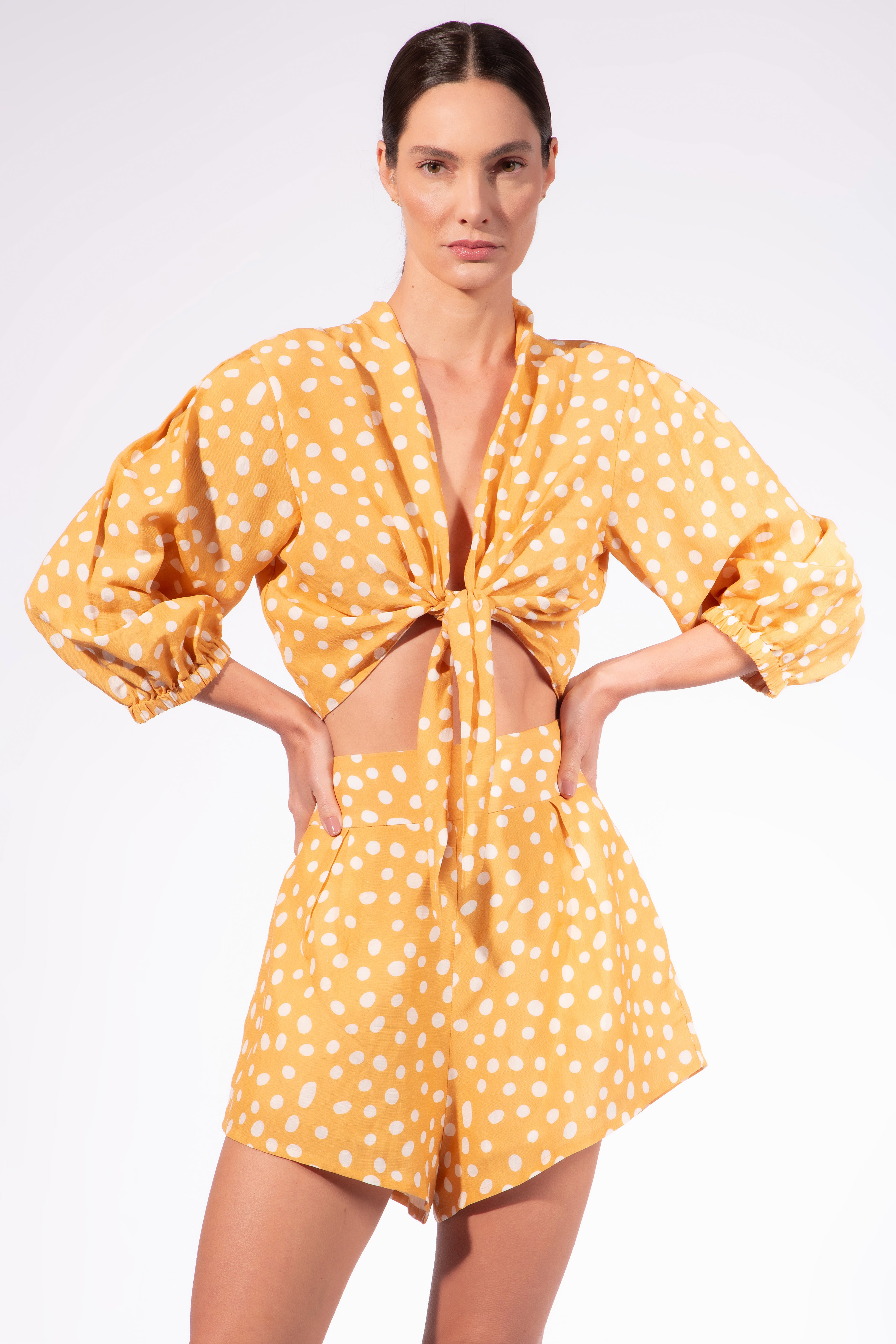 Model wearing the Polka Dots Shorts front color cashew yellow, made from 55% linen 45% viscose, styled for a resort look