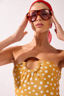 Model wearing the Polka Dots Strapless Sheath detail color cashew yellow, made from 85% polyamide 15% elastane, styled for a beachwear look