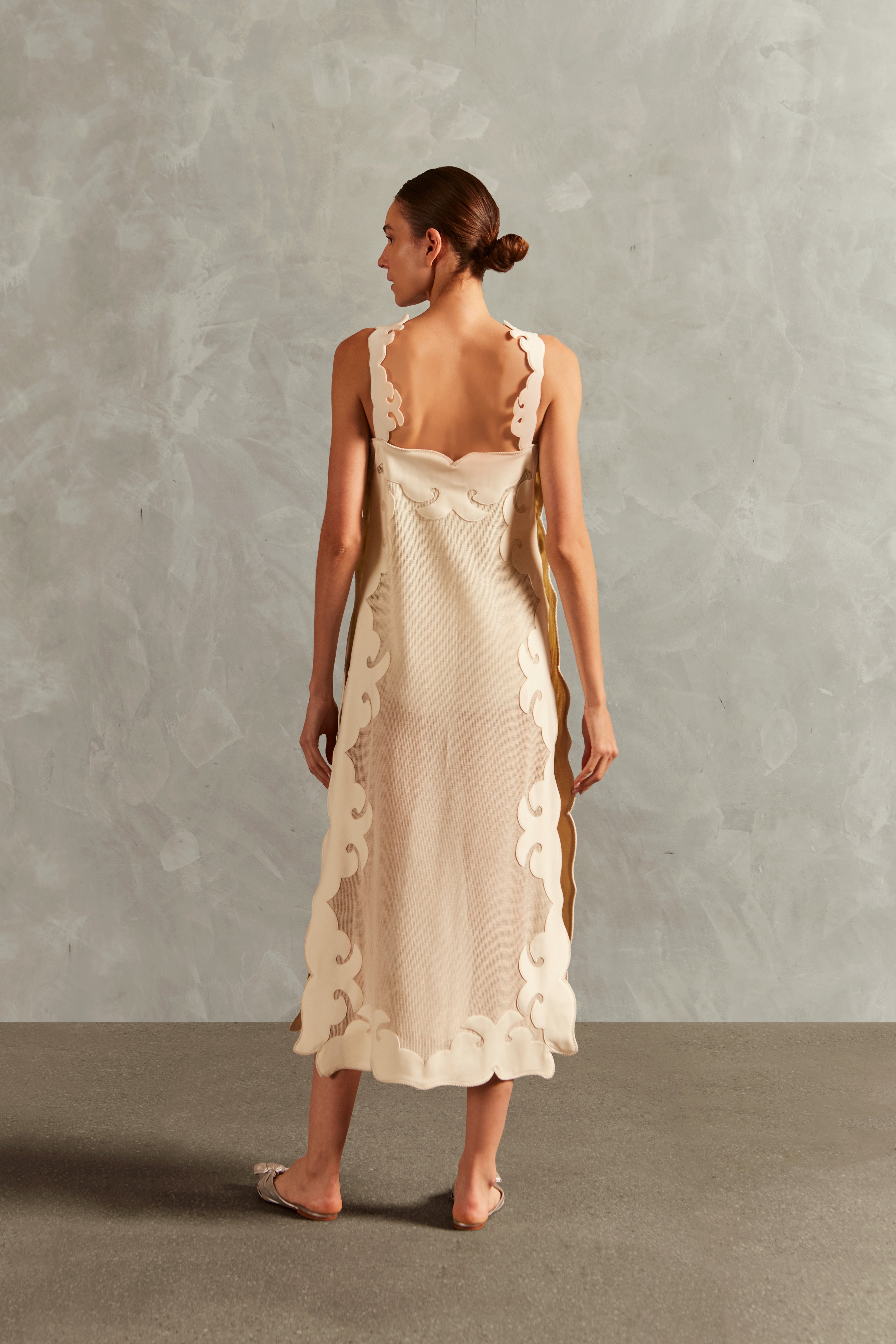 Model wearing the Réseau Appliqué Midi Dress back showcasing its off white color with sheer fabric styled for a post-beach look