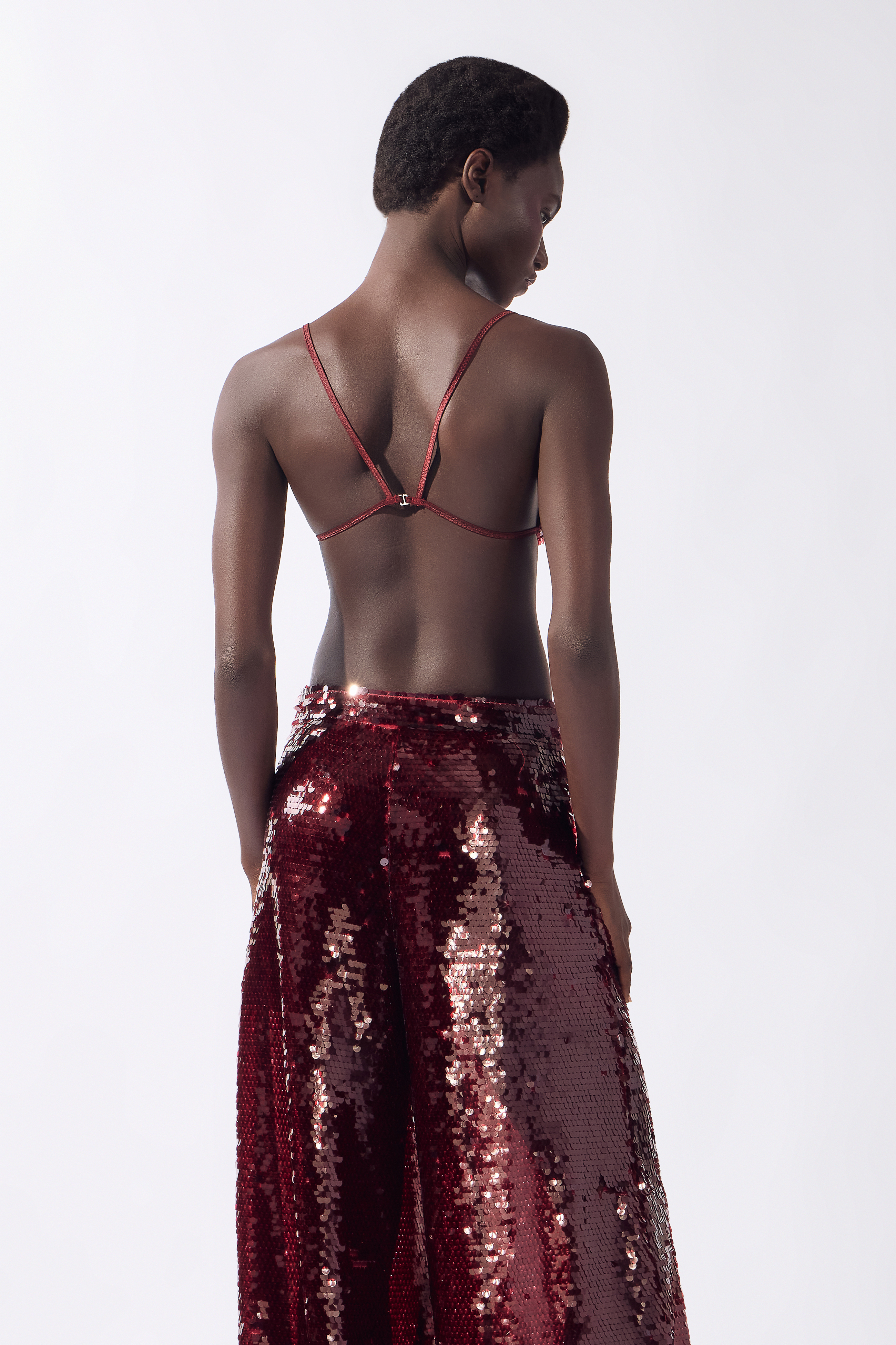 Model wearing the Sequin Bralette Top back color burgundy, made from 100% polyester, styled for a festive look