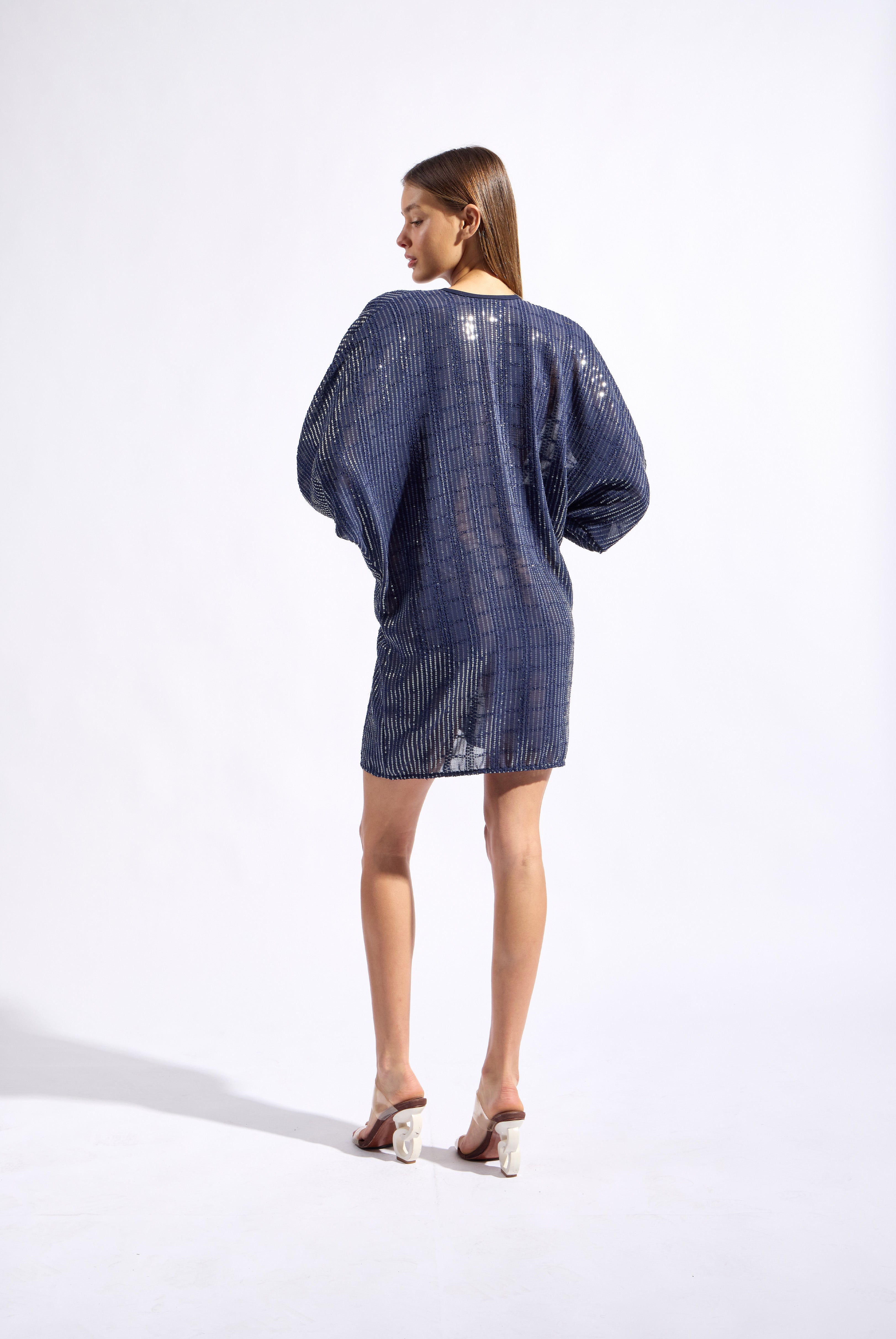 Model wearing the Sequin Front Tie Mini Kaftan back color navy made from 100% polyester, styled for a soiree look