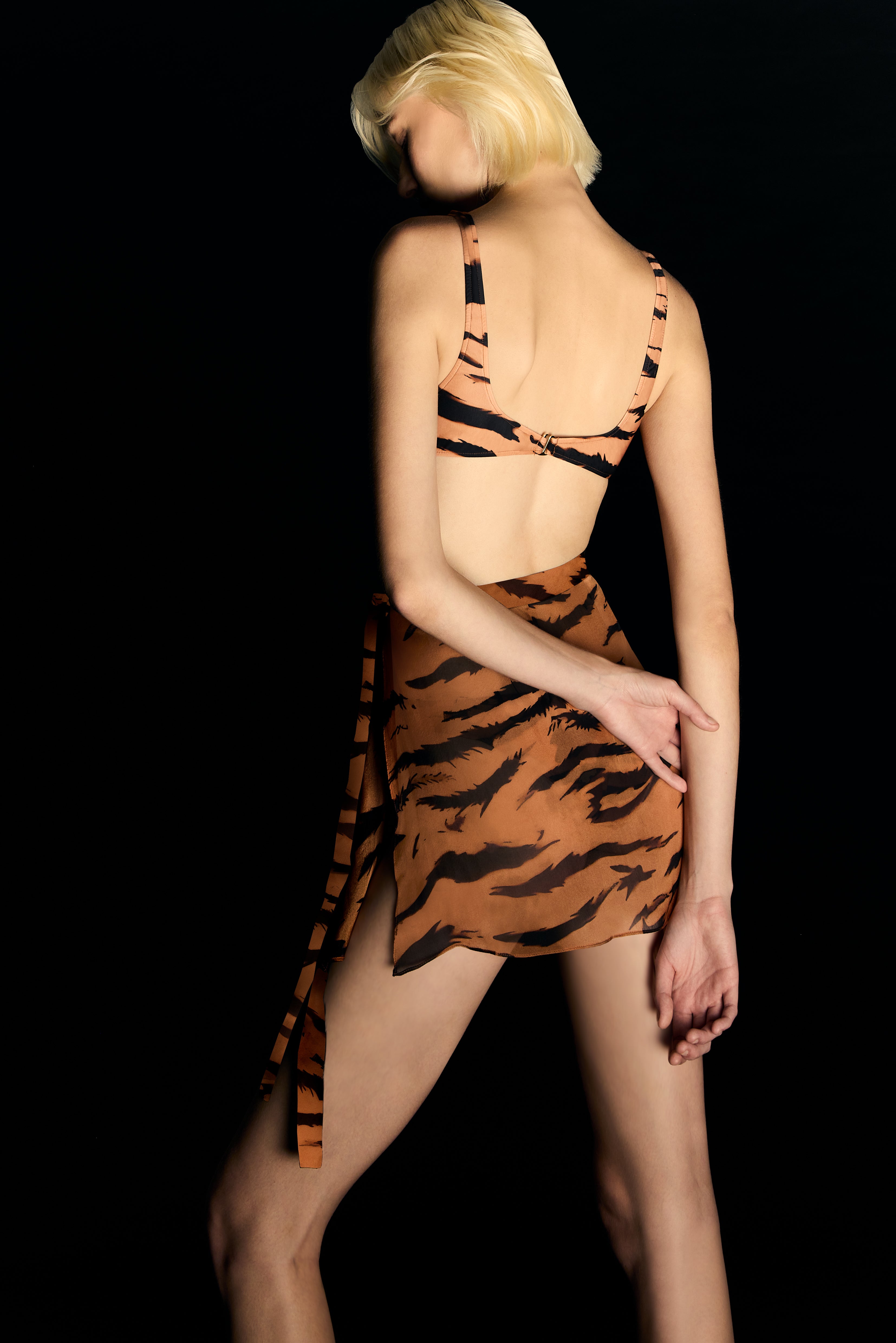 Model wearing the Side-Tie Silk Mini Skirt back from the Adriana Degreas and Sabine Getty collab with 100% Silk styled for a drinks by the pool look.