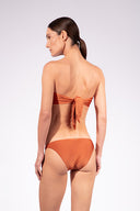 Model wearing the Solid Bandeau Bikini back color cognac made from 85% plyamide 15% elastane, styled for a beachwear look