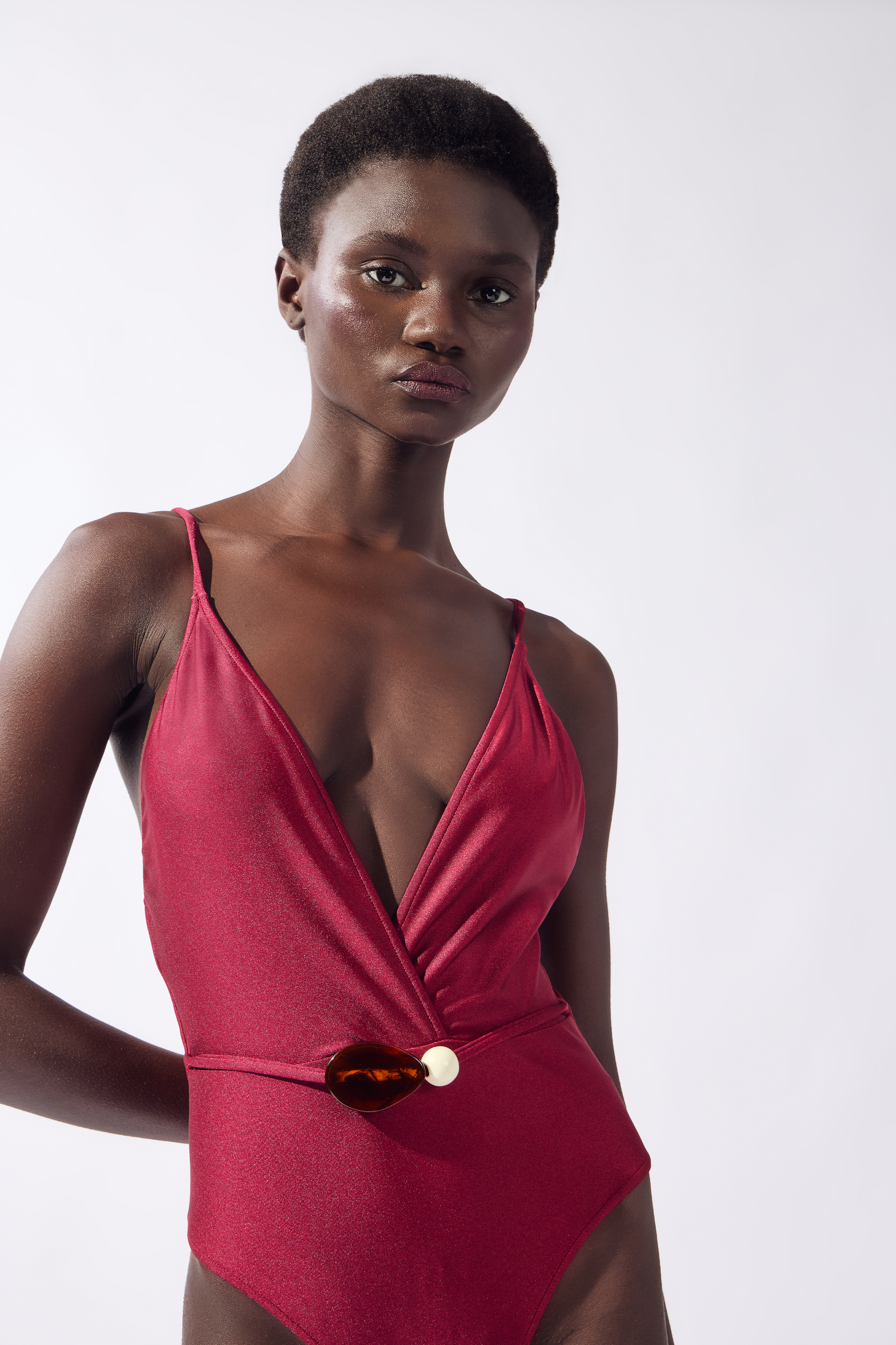 Model wearing the Solid Belted Swimsuit color burgundy made from 85% polyamide 15% elastane, styled for a beachwear look