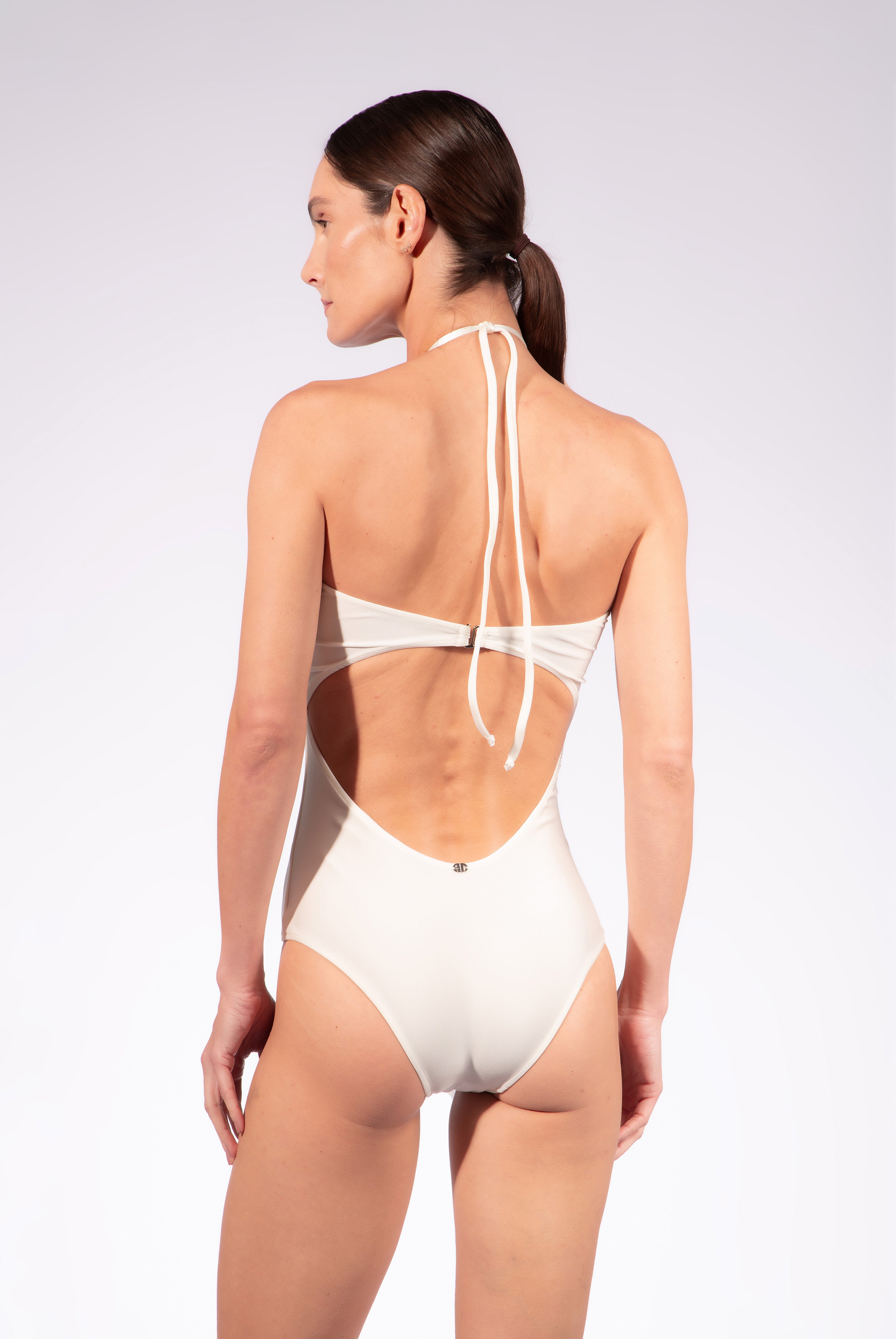 Model wearing the Solid Chain Halterneck Swimsuit back color off white made from 85% polyamide 15% elastane, styled for a beachwear look
