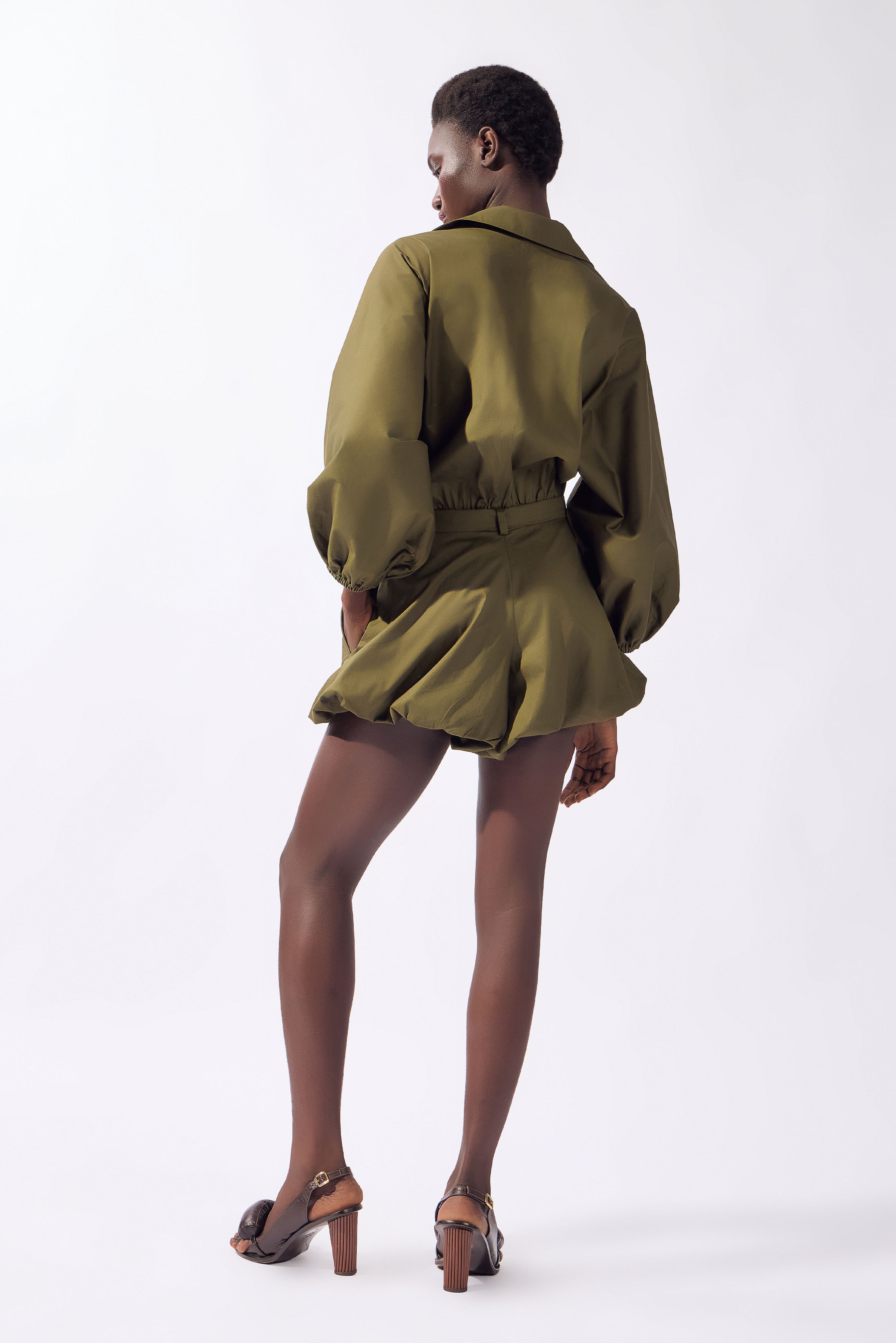 Model wearing the Solid Deep V-Neck Playsuit back, color green, made from 98% cotton 2% elastane, styled for a resort look