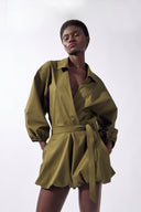 Model wearing the Solid Deep V-Neck Playsuit detail, color green, made from 98% cotton 2% elastane, styled for a resort look