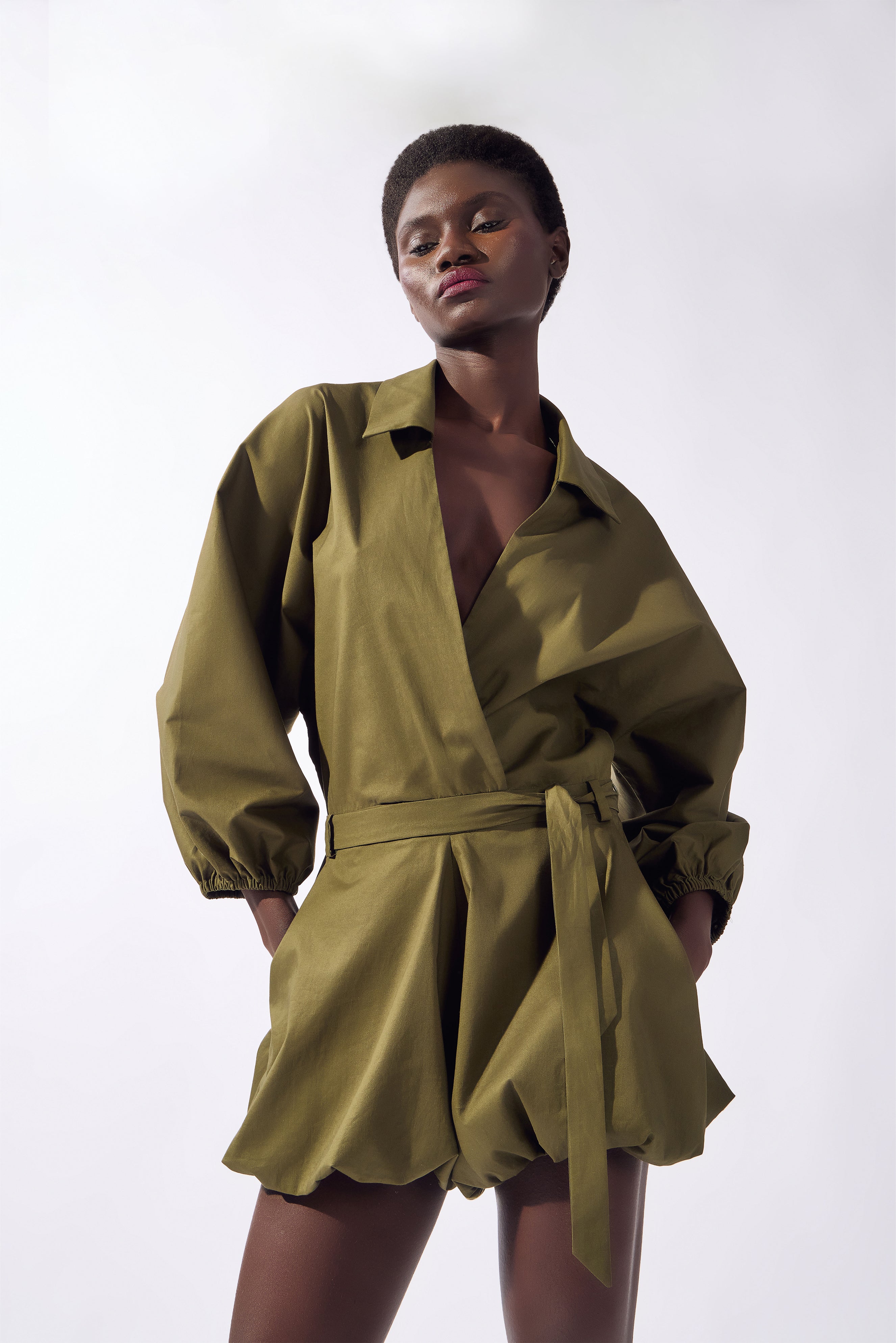 Model wearing the Solid Deep V-Neck Playsuit detail, color green, made from 98% cotton 2% elastane, styled for a resort look