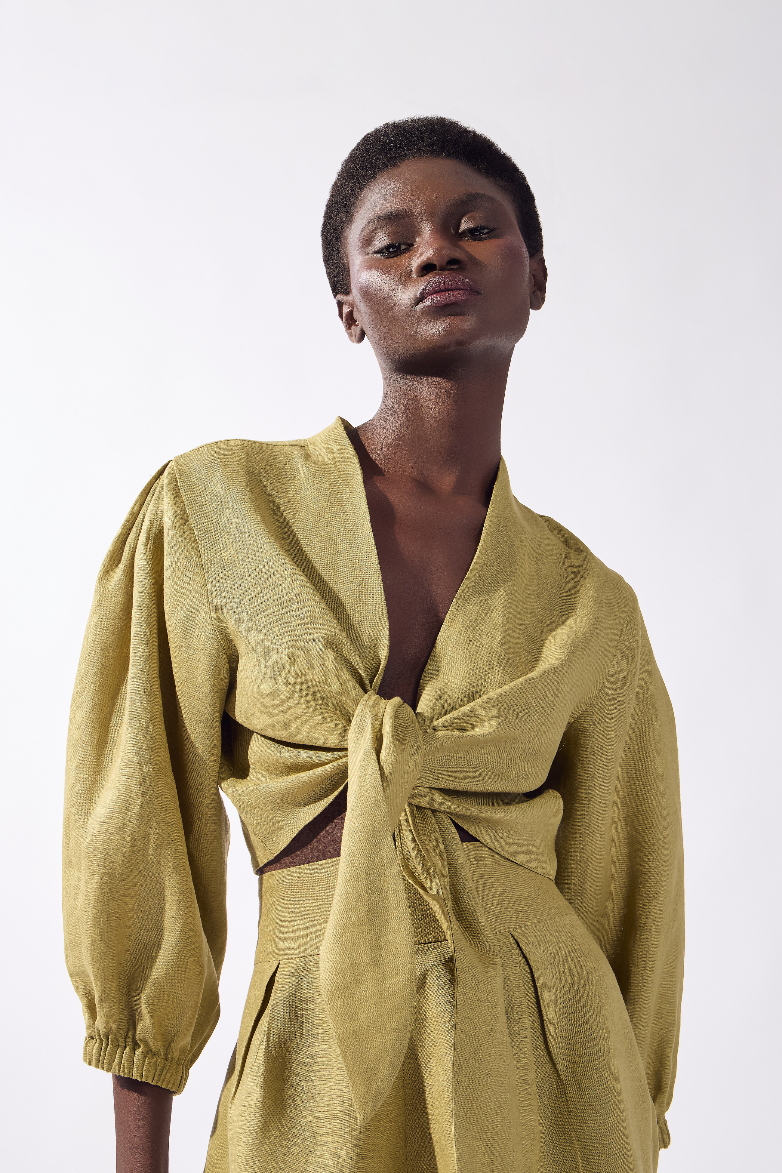Model wearing the Solid Front-Tie Crop Top detail color pistachio, made from 100% linen, styled for a resort look