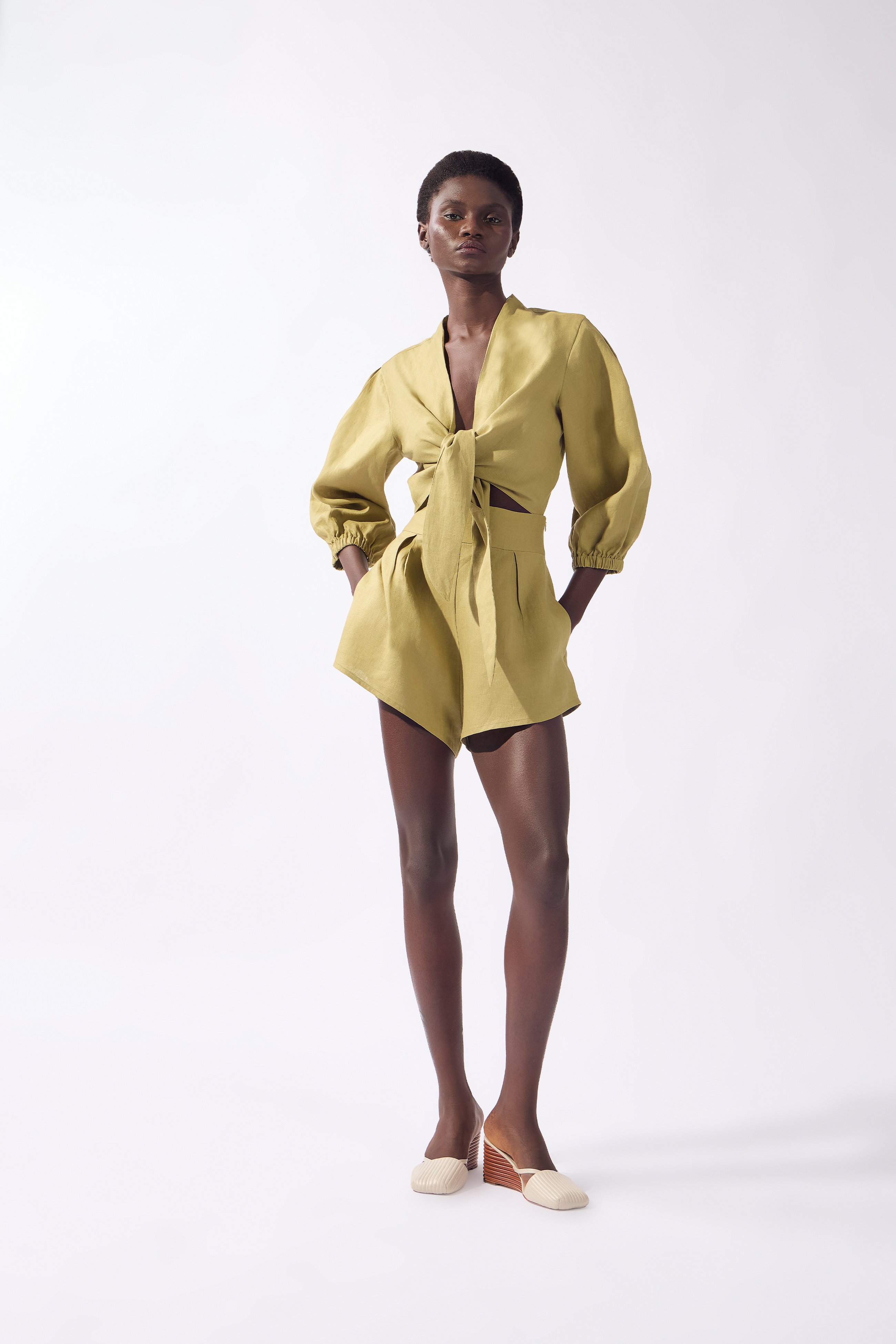 Model wearing the Solid Front-Tie Crop Top front color pistachio, made from 100% linen, styled for a resort look