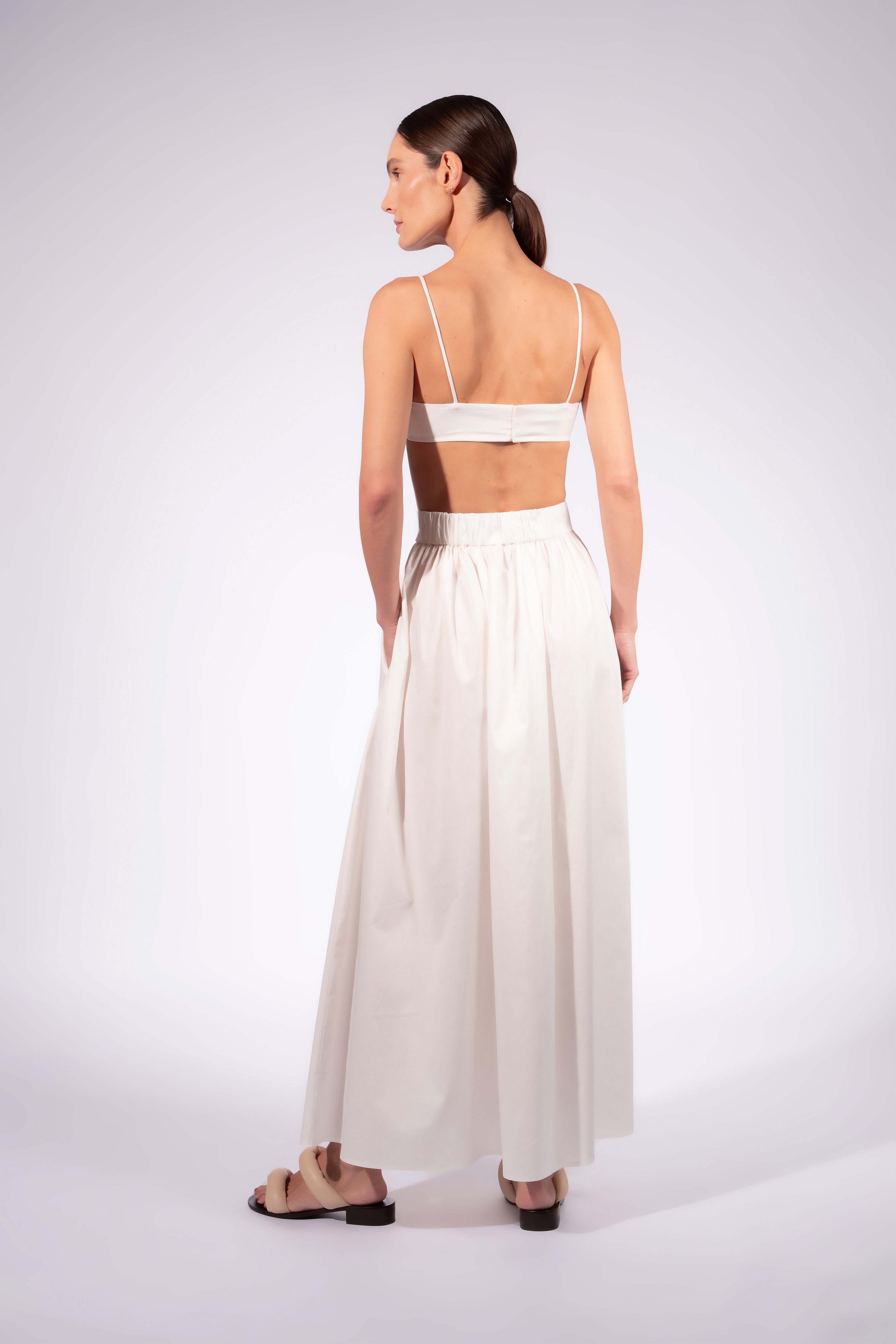 Model wearing the Solid Maxi Skirt back front color off white made with 98% Cotton 2% Elastane, styled for resortwear look