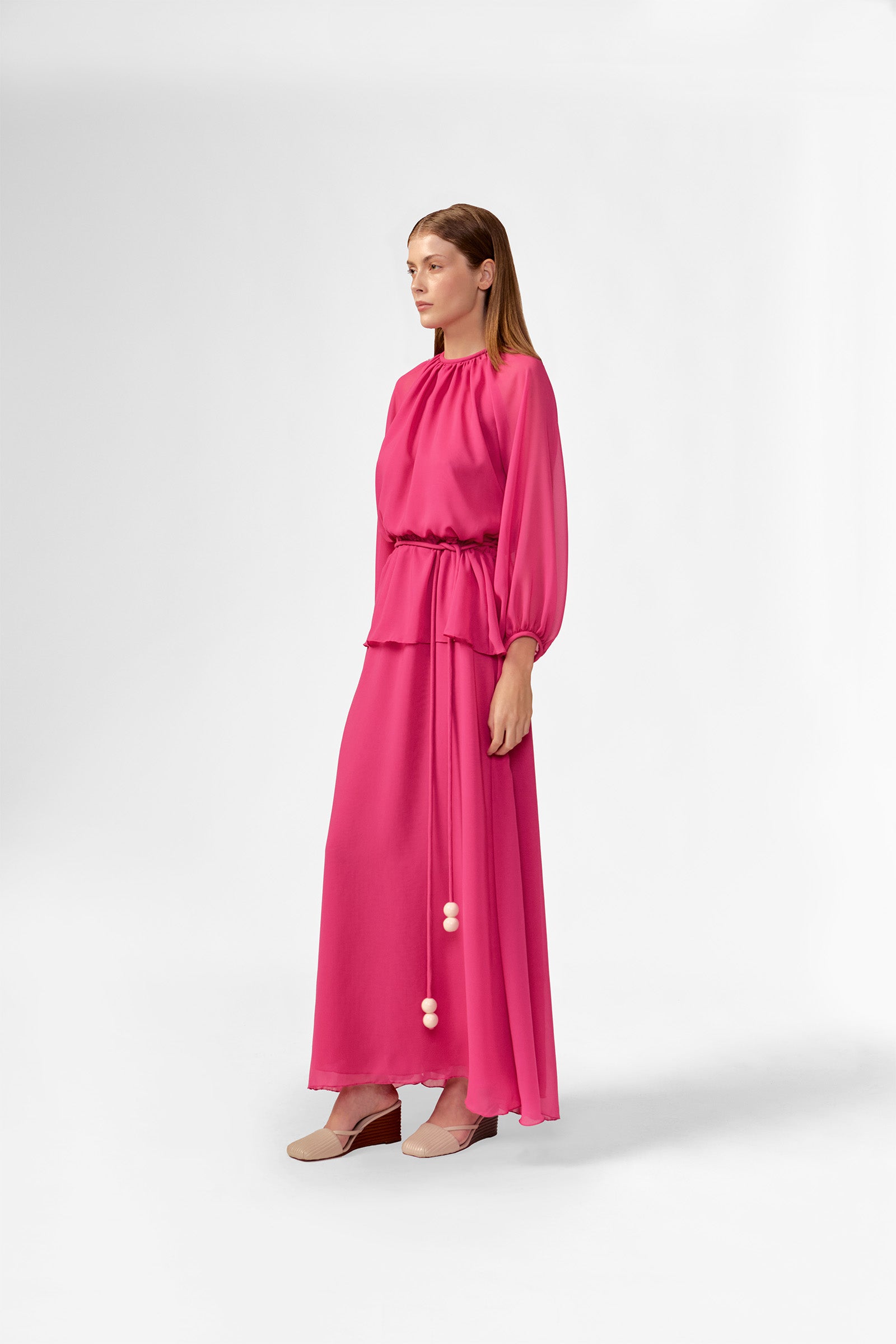 Model wearing the Solid Peplum Maxi Dress detail color pink made with 100% Cotton, styled for resortwear look