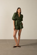 Model wearing the Solid Pleated Shorts dark green front from the HS25 with 98% cotton 2% elastane styled for a lunch look.    