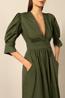 Model wearing the Solid Puff-Sleeved Long Dress detail color dark green with 98% cotton and 2% elastane fabric styled for a resort look