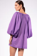 Model wearing the Solid Puff Sleeve Mini Dress back color purple made with 100% Cotton,  styled for resortwear look 