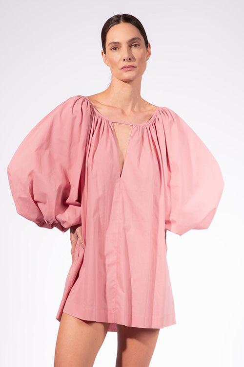 Model wearing the Solid Puff Sleeve Mini Dress detail color pink made with 97% Cotton 3% Elastane,  styled for resortwear look 
