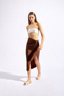 Model wearing the Solid Ruched Midi Skirt front in cappuccino color, made from 85% polyamide 15% elastane fabric, styled for a resort look