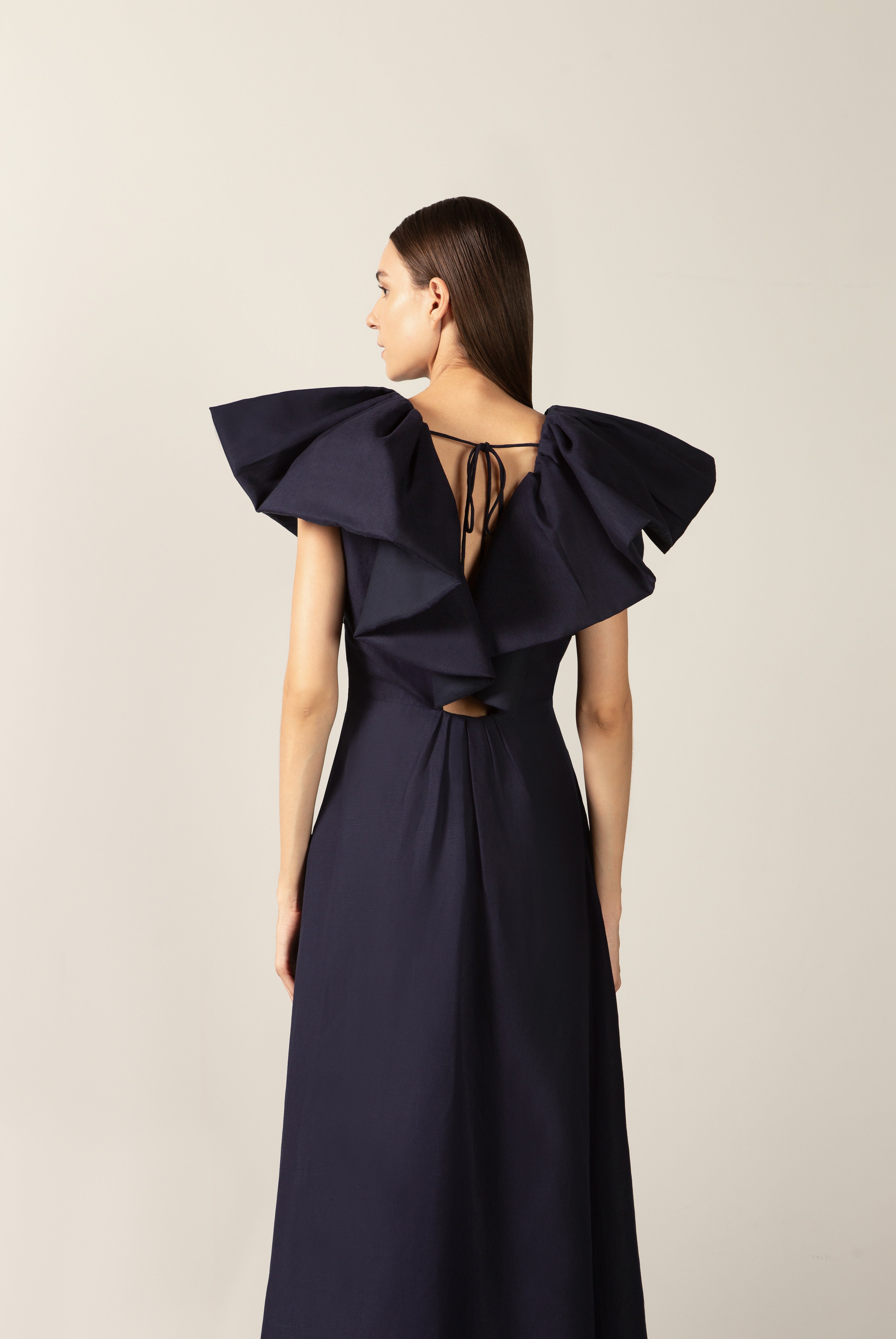 Model wearing the Solid Ruffled Maxi Dress back color navy made with 55% viscose 45% Linen, styled for resortwear look