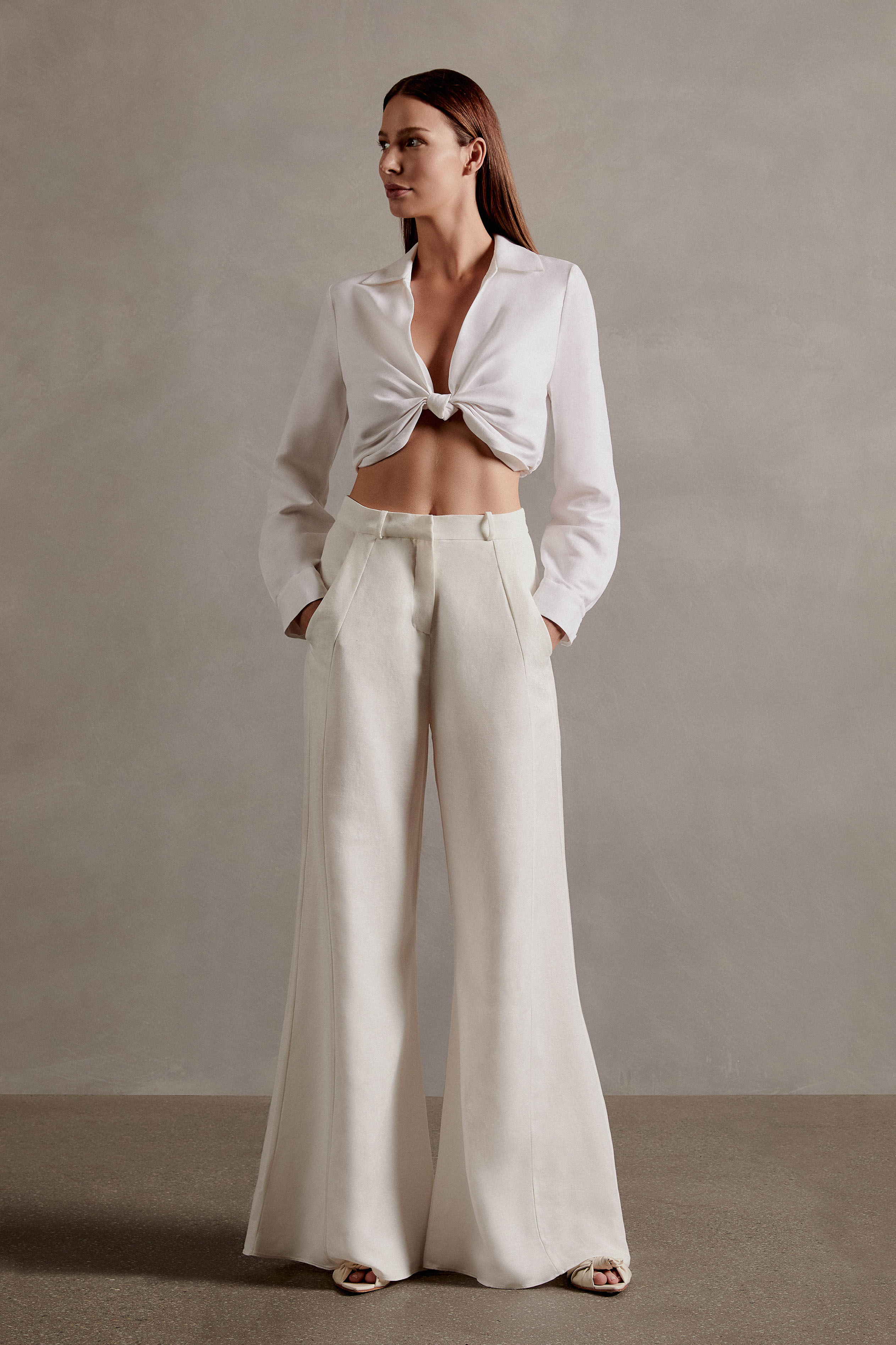 Model wearing he Front olf the Timeless Wide-Leg Pants, with off white color and 55% VISCOSE 45% LINEN fabric, styled for a resort look
